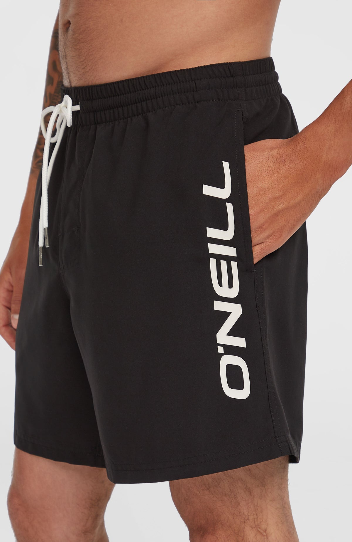 Cali 16'' Badehose für Herren, schwarz, Seitenansicht am Model, vertikaler weißer Logo-Print am Hosenbein