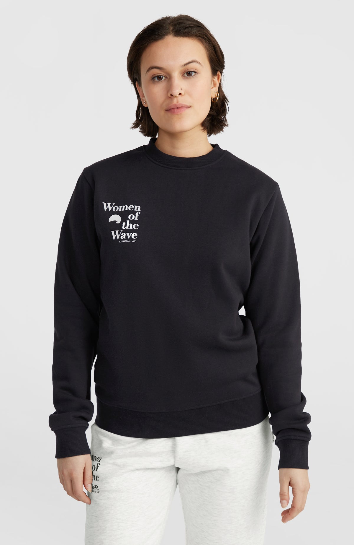 O'Neill Women of the Wave Crew Sweatshirt für Damen, schwarz mit Logo-Print in Weiß, Vorderansicht getragen am Model
