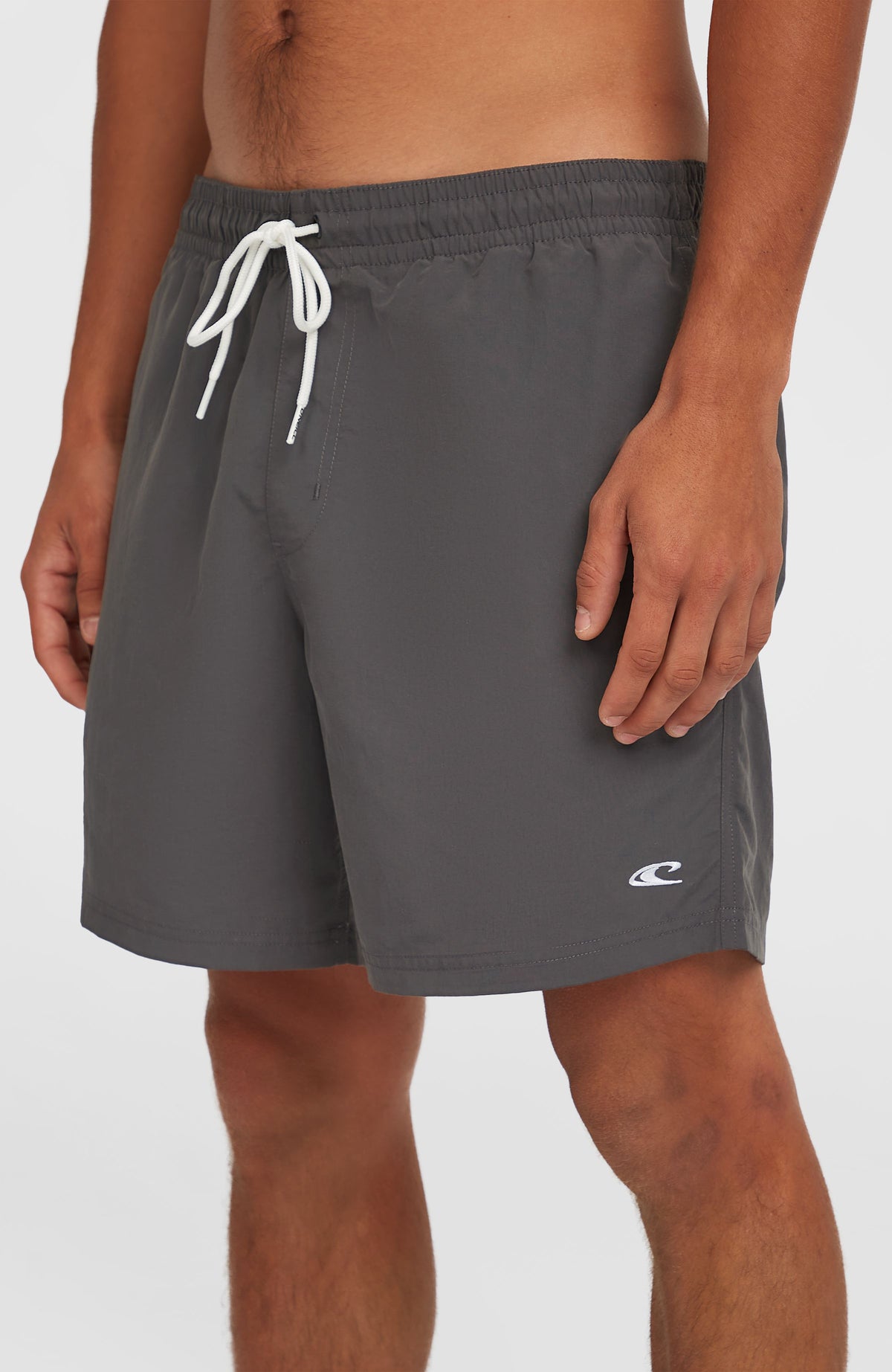 Nahaufnahme der grauen Vert 16" Badehose am Model mit weißem Kordelzug und kleinem Logo am Saum