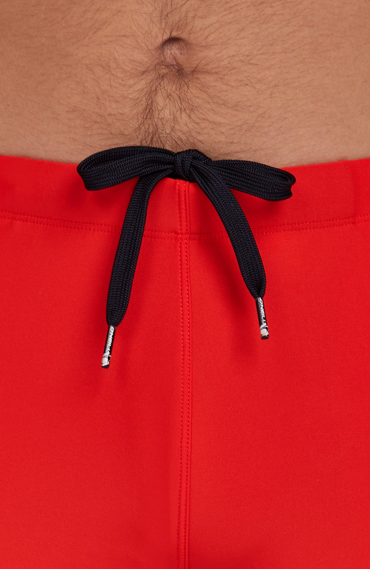 Nahaufnahme von Bund und schwarzem Kordelzug der roten Essentials Racer Badehose am Model