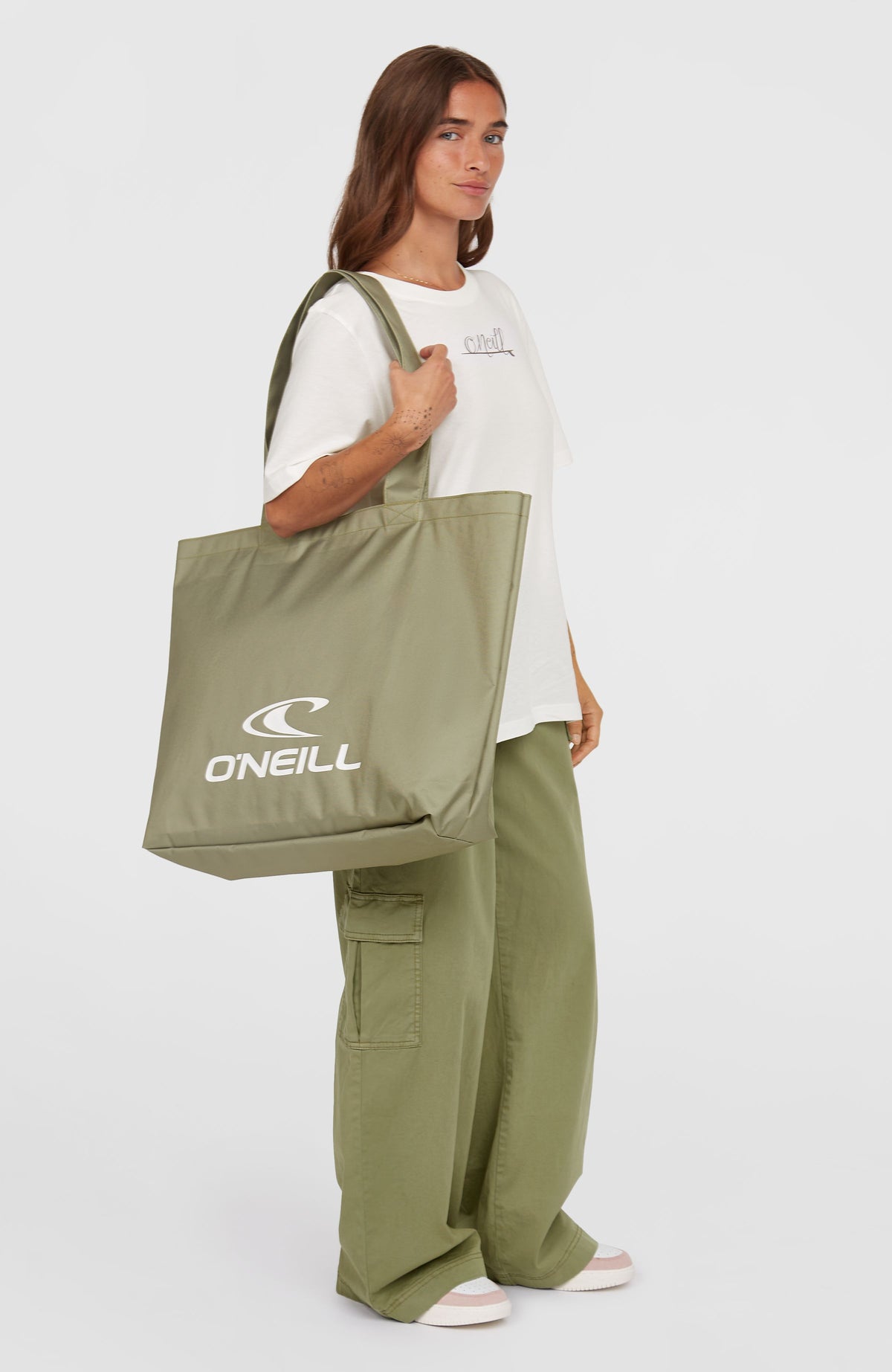 Coastal Tote Bag Tasche für Damen, grün mit Logo-Print in Weiß, getragen am Model in Seitenansicht