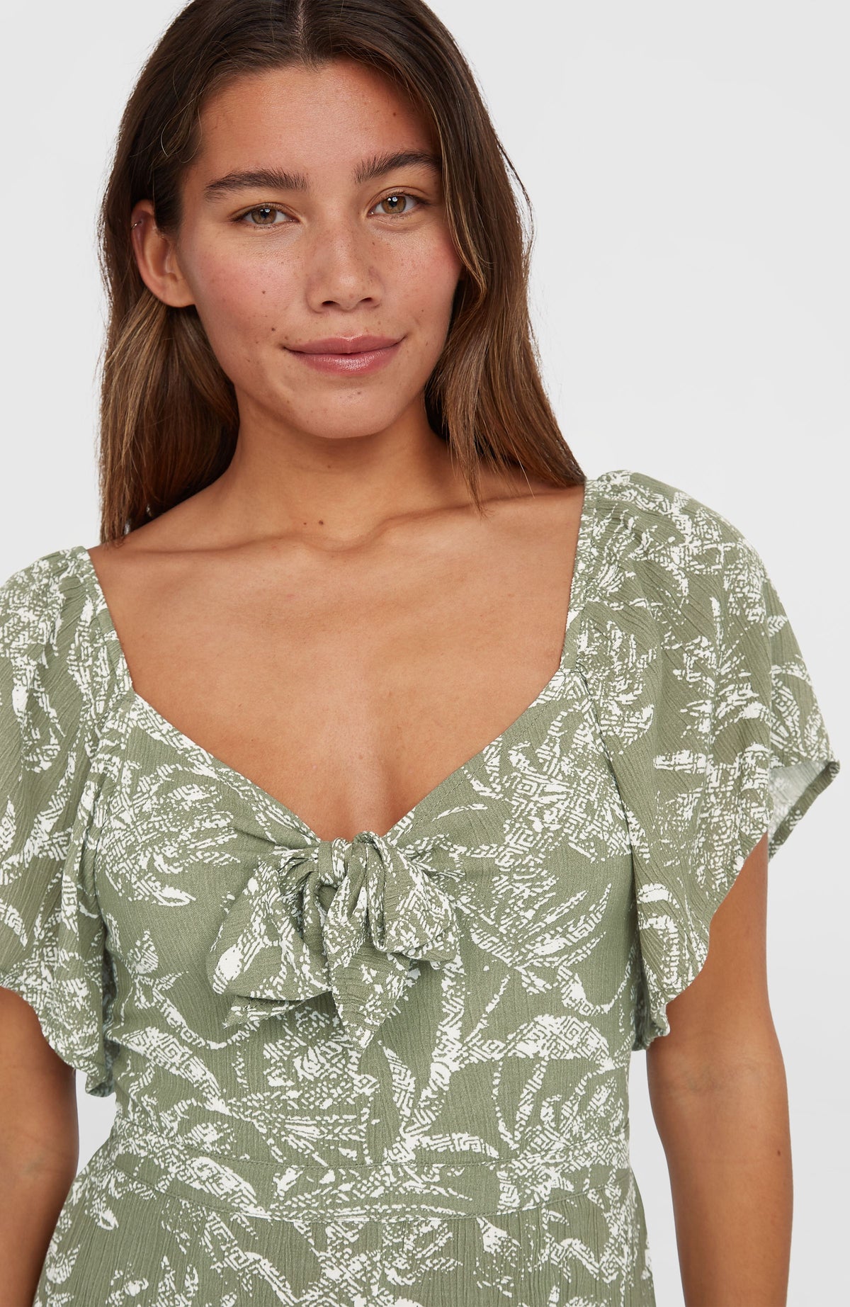 Kesia Jumpsuit für Damen, grün mit Dschungelmuster in Weiß, Nahaufnahme des Ausschnitts mit Bindedetail am Model