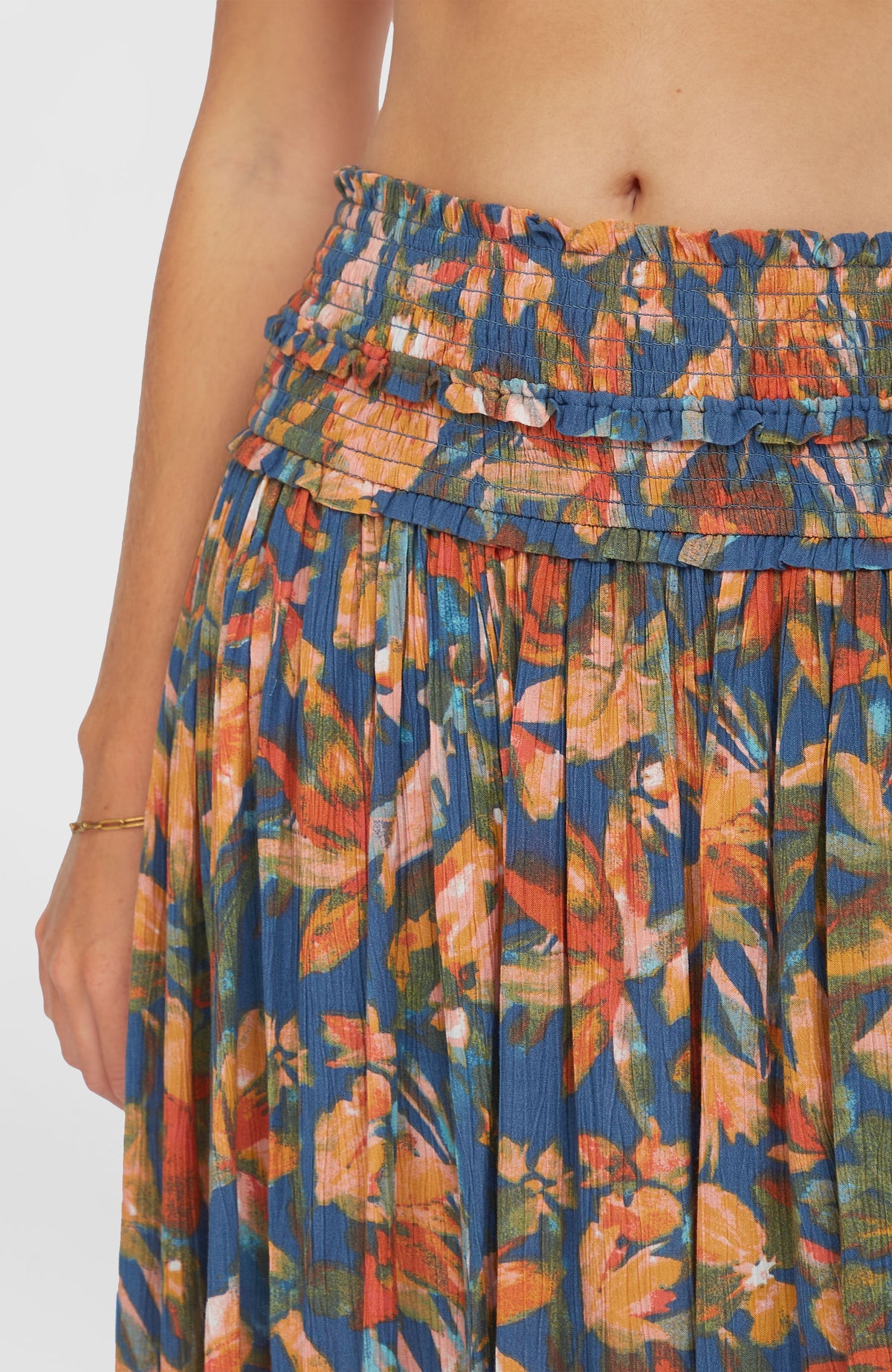 Nahaufnahme des gesmokten Bundes mit Rüschendetail am blauen Devyn Maxirock mit Blumenmuster in Orange und Gelb