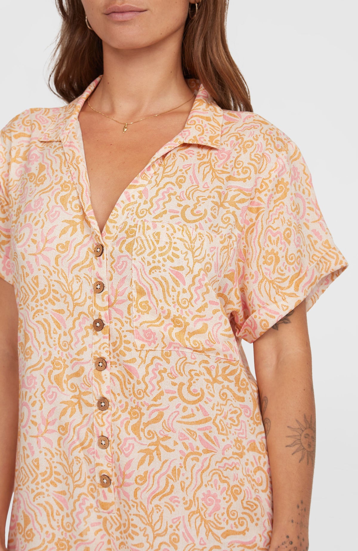 Nahaufnahme der Knopfleiste des weißen Women of the Wave Romper Jumpsuits mit Wellenmuster in Gelb und Rosa am Model