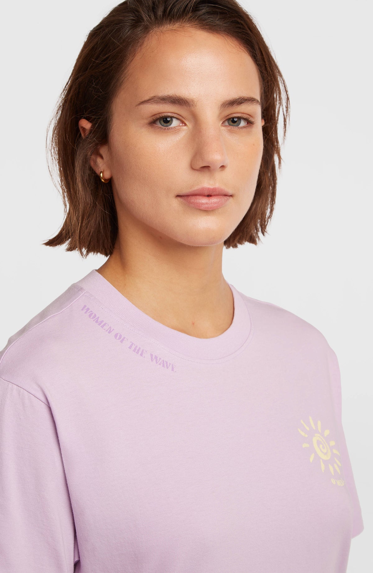 Nahaufnahme von Rundhalsausschnitt und kleinem Print des lila Women of the Wave T-Shirt-Kleids am Model