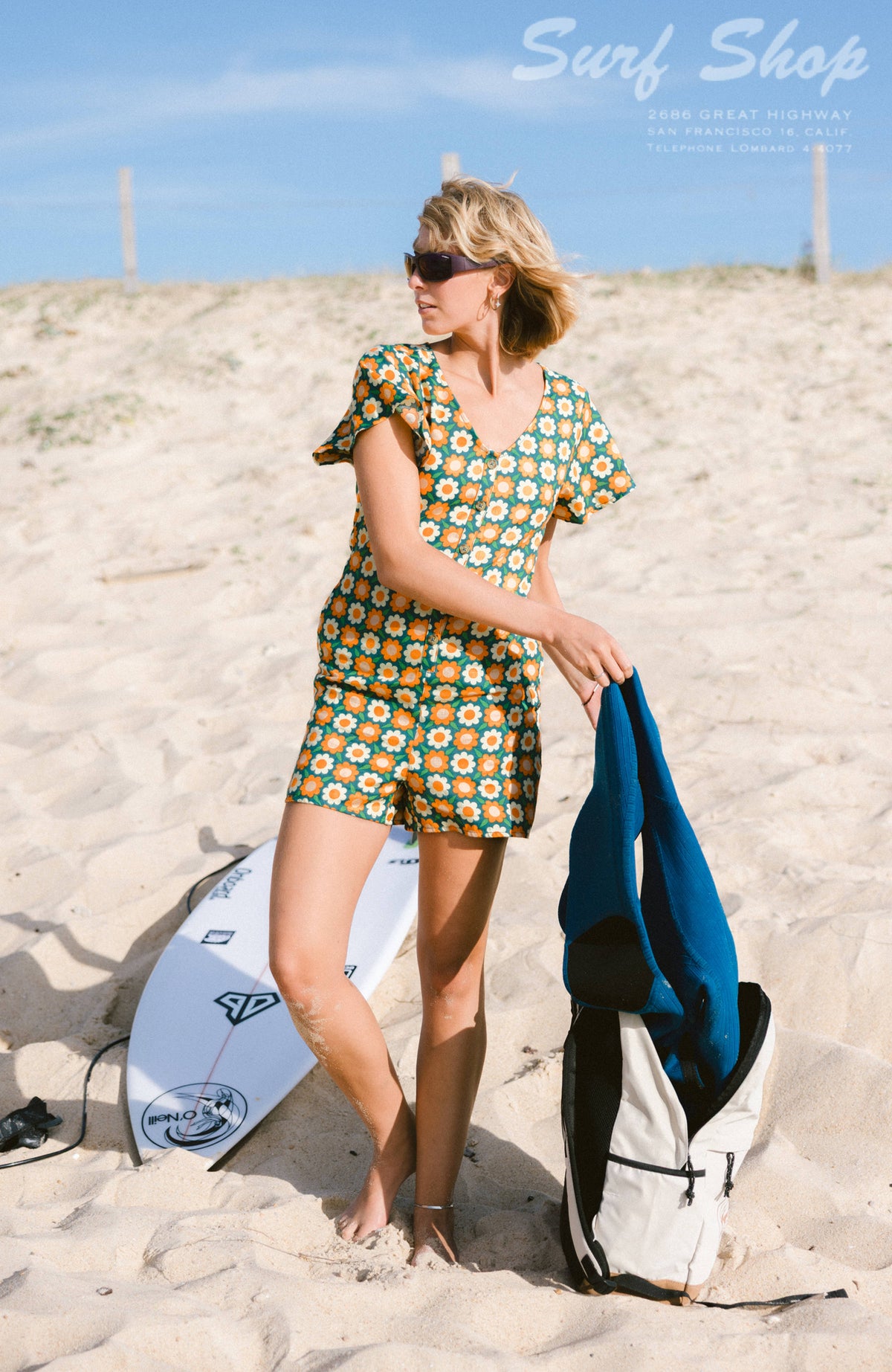 O'Riginals Playsuit für Damen, grün mit Blumenmuster in Orange und Gelb, getragen am Model in den Dünen am Strand