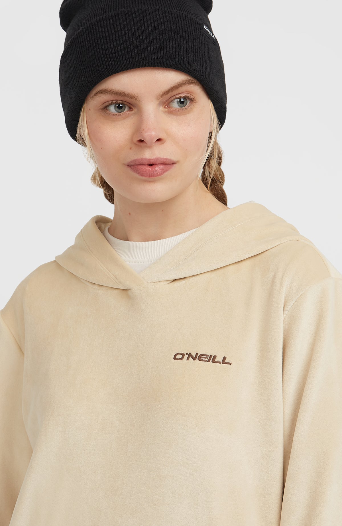 Nahaufnahme des beigen FWC'Cruz Velour Hoodie für Damen am Model mit Kragen und Logo-Stickerei
