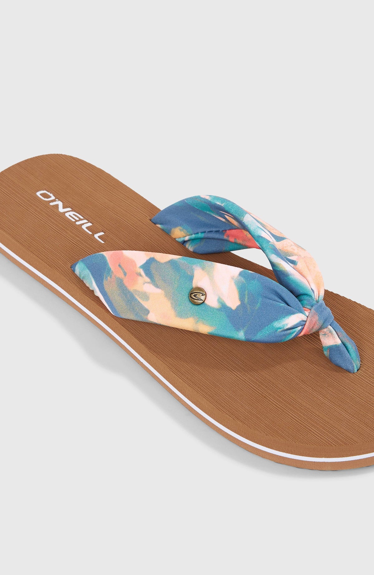 Blaue Ditsy Sun Sandalen für Damen mit Tropenmuster, Nahaufnahme des geknoteten Riemens mit Logo-Pin