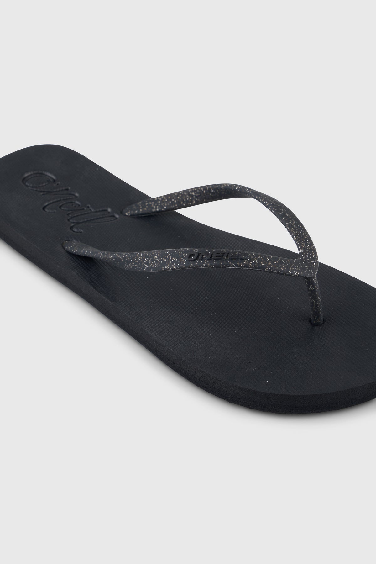 Nahaufnahme des Zehentrenner-Riemens der schwarzen Profile Glitter Sandalen
