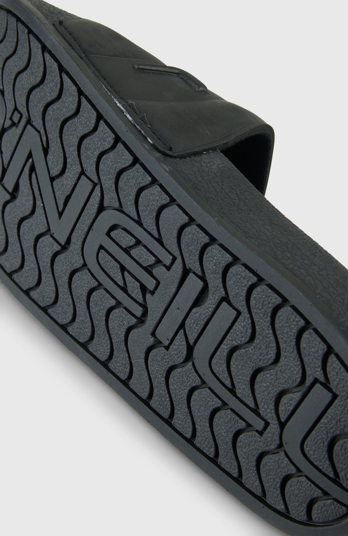 Nahaufnahme der profilierten Sohle der schwarzen Embossed Slides für Damen