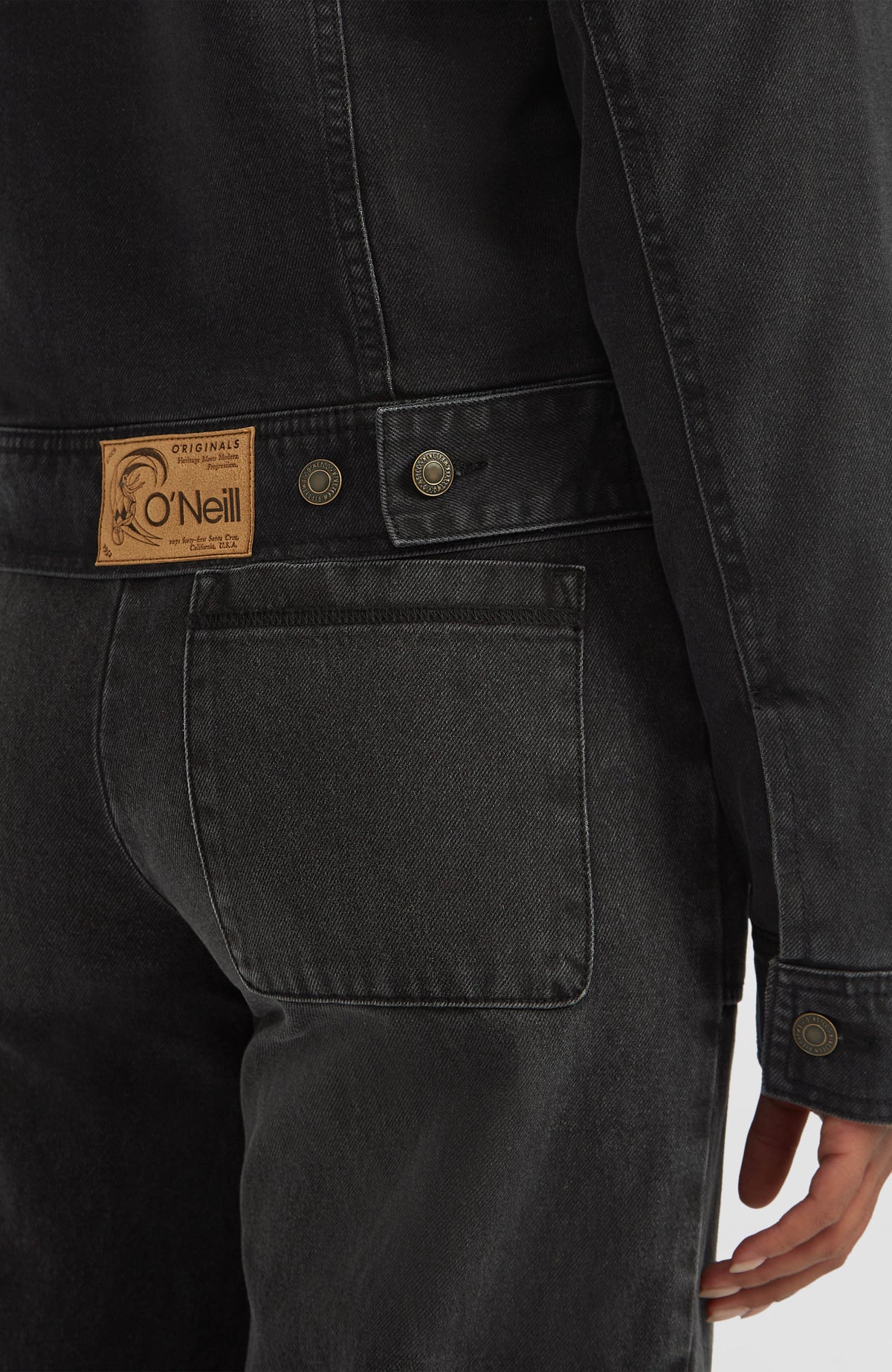 O'Riginals Jeansjacke für Damen in Schwarz, Nahaufnahme der Rückseite mit Knopfriegel und Logo-Badge am Model