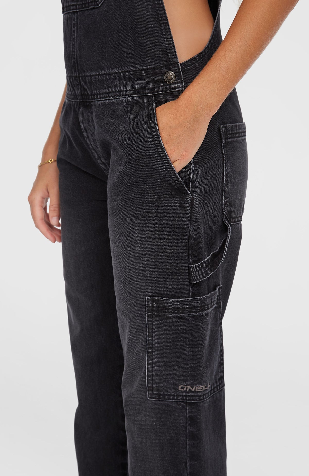 Nahaufnahme der aufgesetzten Tasche am Hosenbein der schwarzen Essentials Twill-Latzhose