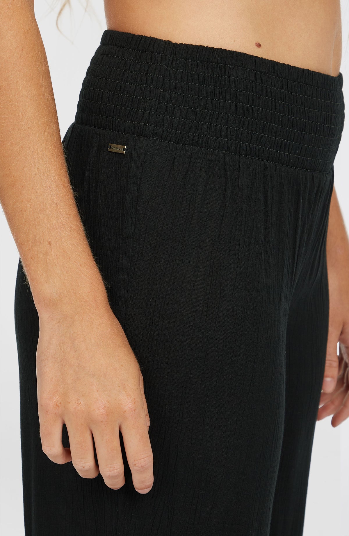 Nahaufnahme des Smokbunds mit Metall-Logo der schwarzen Johnny Smocked Waist Hose