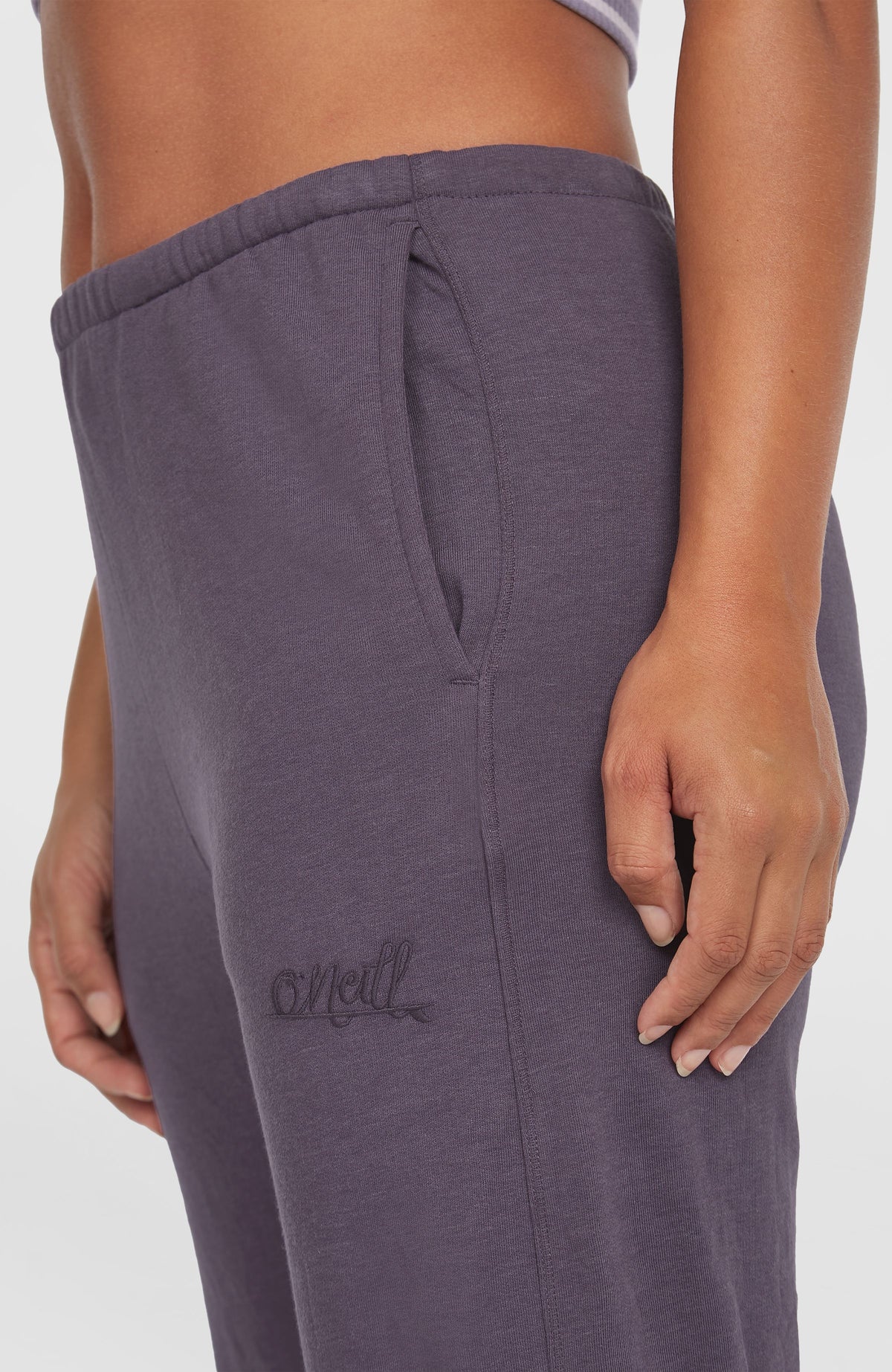 Nahaufnahme der lila Essentials O'Neill Script Jogginghose am Model mit Seitentasche und gesticktem Schriftzug