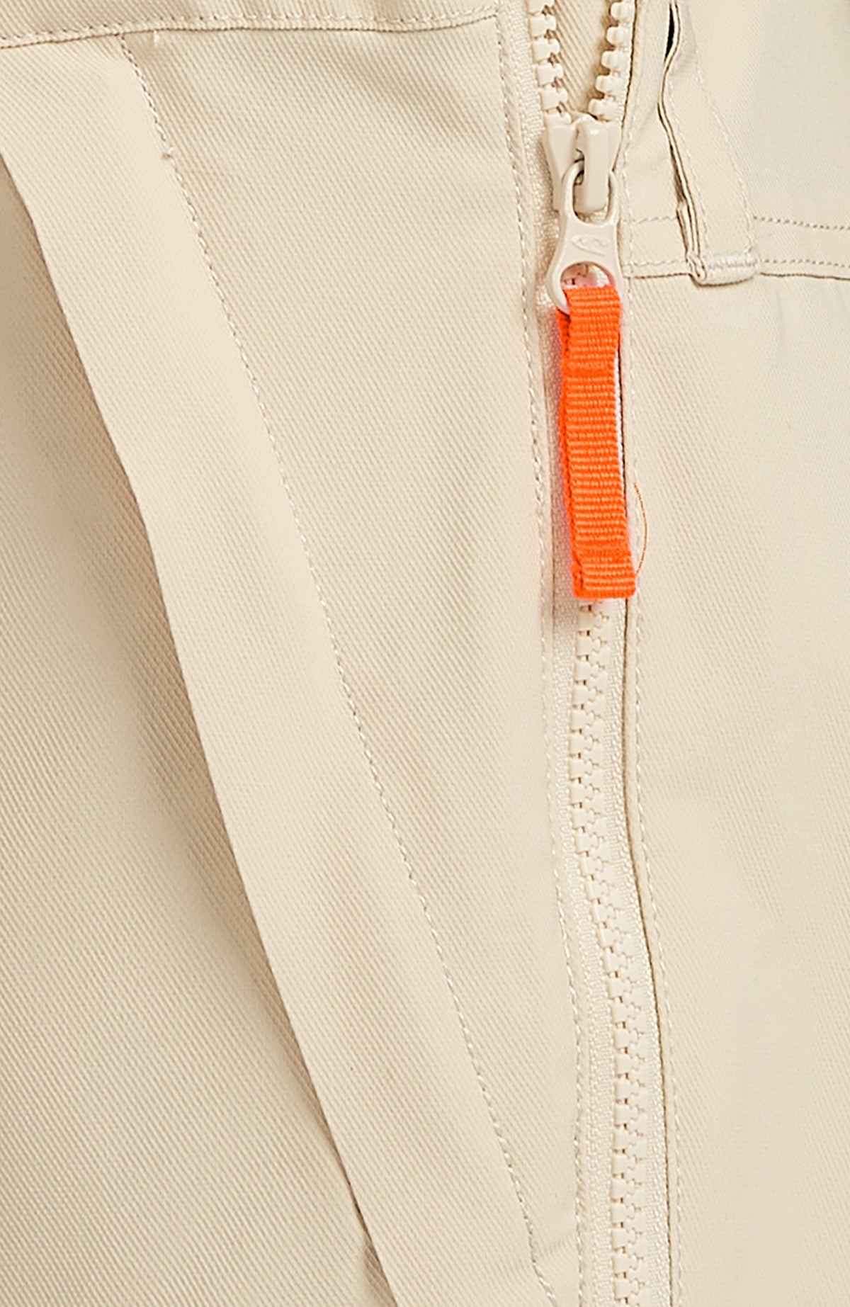 Detailaufnahme des Reißverschlusses mit orangefarbenem Anhänger an der beigen FWC'Peak Bib Skihose
