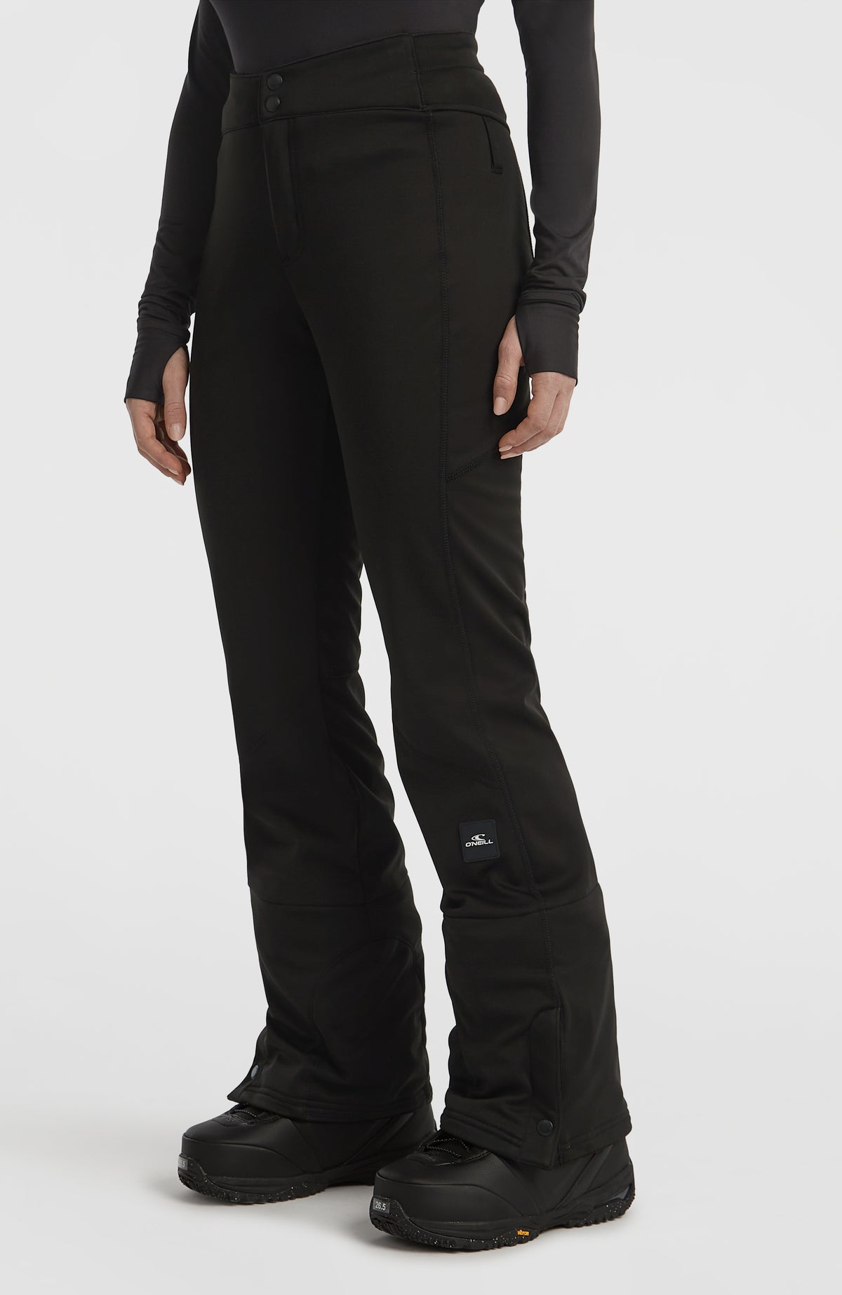 FWC'Cruz Softshell-Skihose für Damen in Schwarz, Schrägansicht getragen am Model mit Logo-Patch am Hosenbein