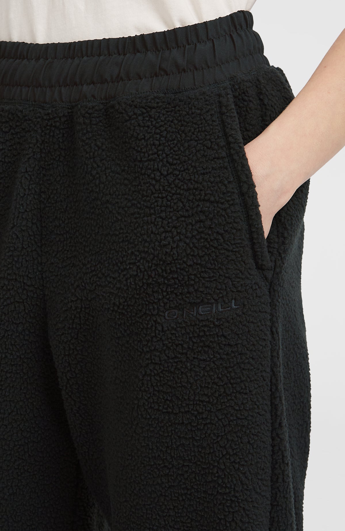 Nahaufnahme der schwarzen Flauschige Must-Have Jogginghose am Model, Seitentasche mit Logo-Stickerei