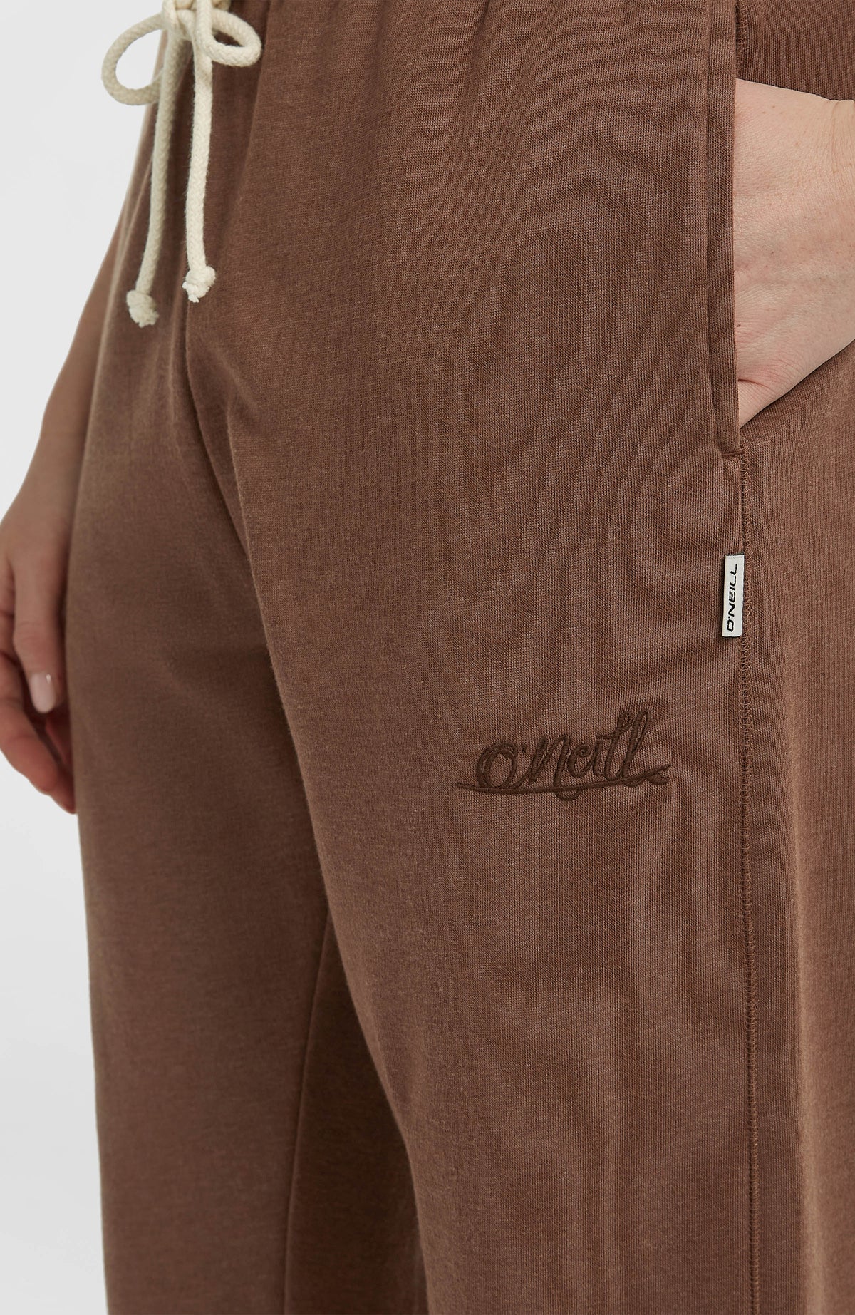 Nahaufnahme der braunen Essentials Script Jogginghose mit Logo-Stickerei und Kordelzug am Bund