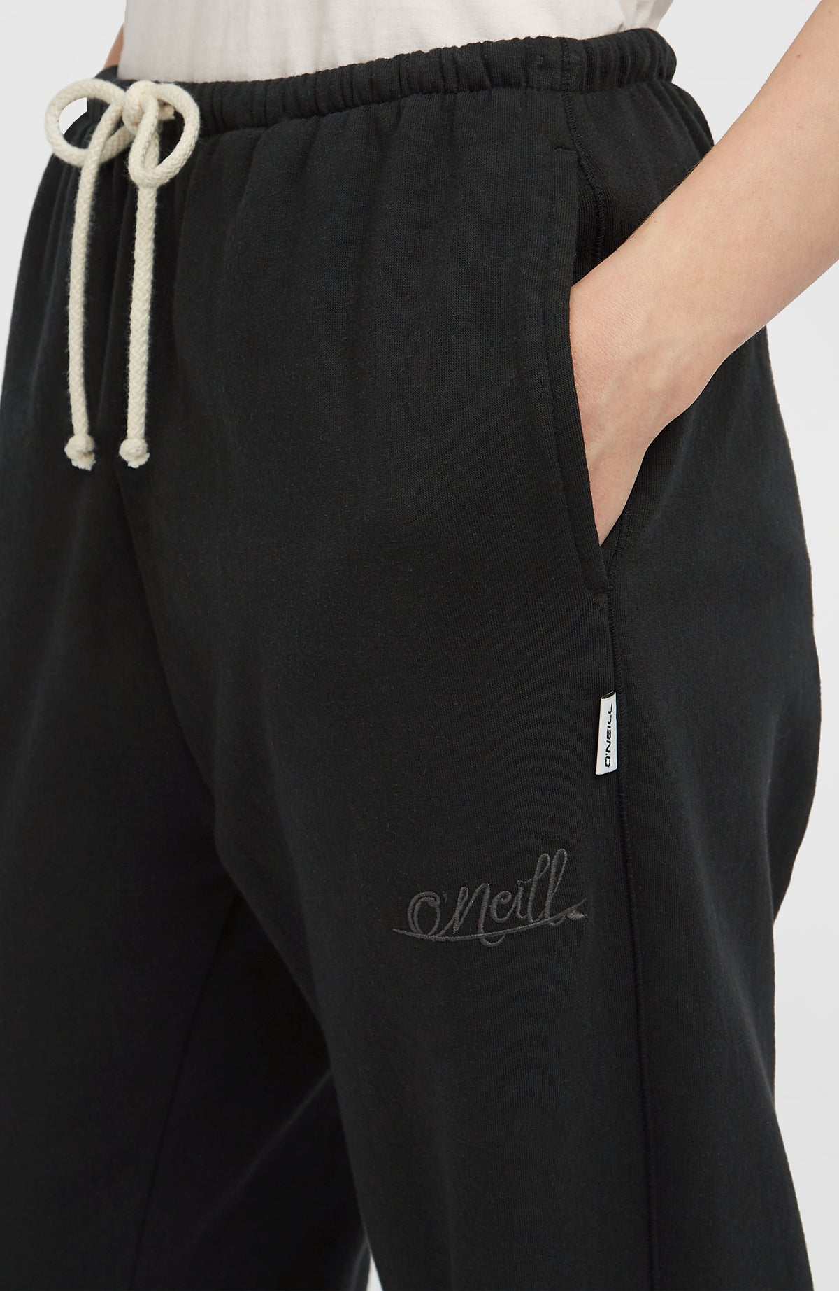 Nahaufnahme der schwarzen Essentials Script Jogginghose mit sichtbarer Seitentasche und kleinem Logo-Detail