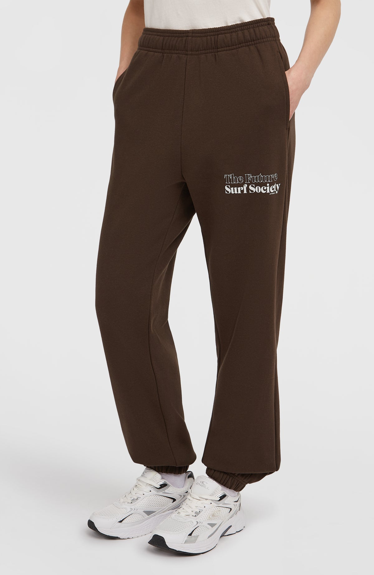 Future Surf Society Jogginghose für Damen, braun mit Logo-Print in Weiß, getragen am Model in Dreiviertelansicht