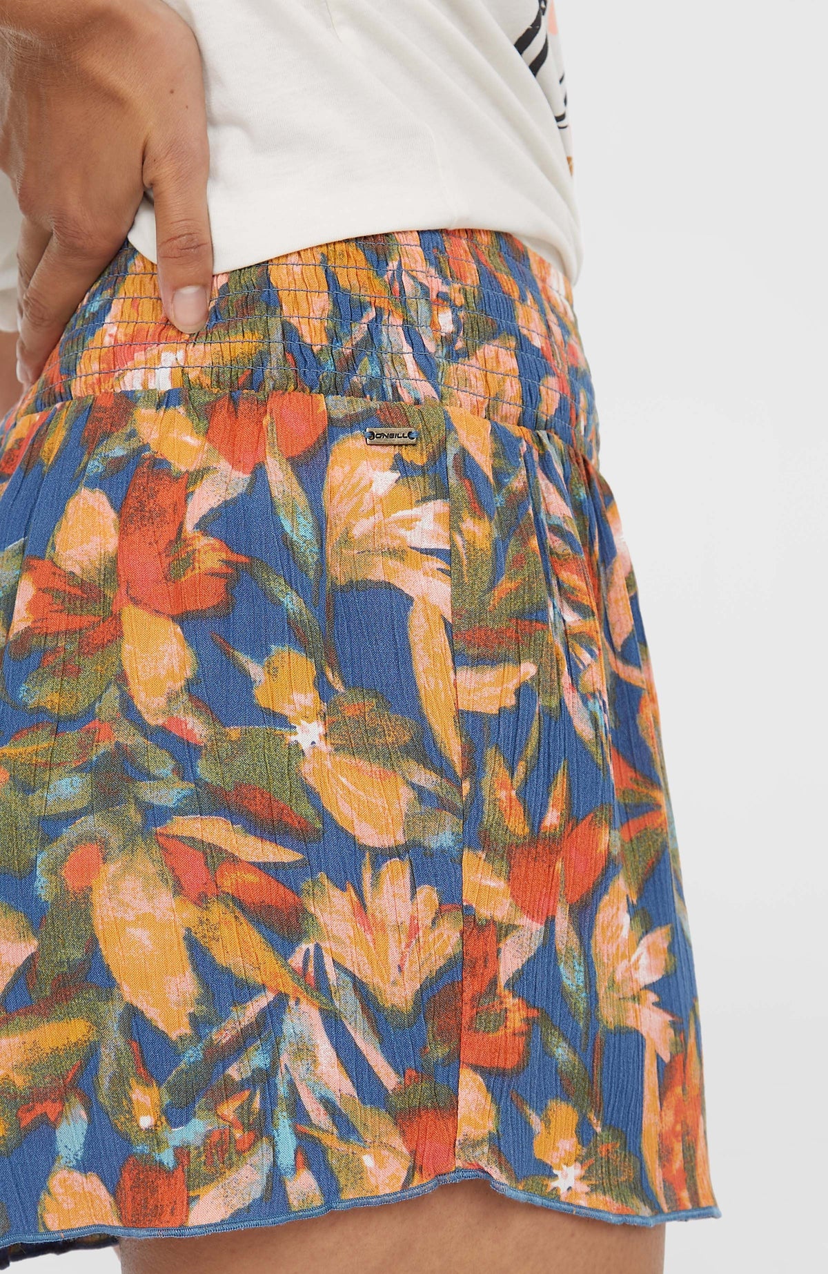 Nahaufnahme des gesmokten Bundes der blauen Johnny Smocked Waist Shorts für Damen mit Logo-Badge