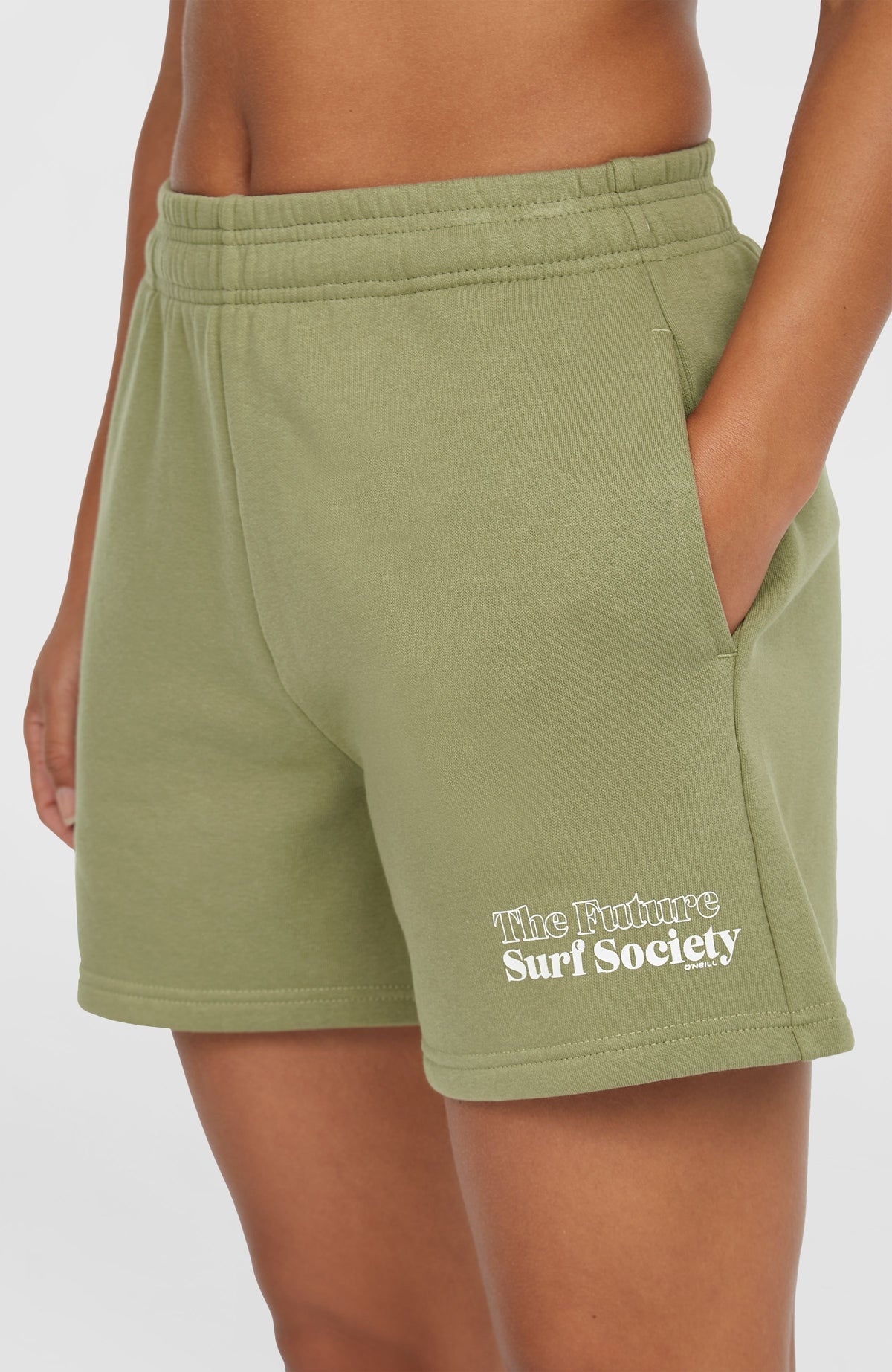 Nahaufnahme der Seitentasche an den grünen Future Surf Society Shorts für Damen mit Logo-Print in Weiß
