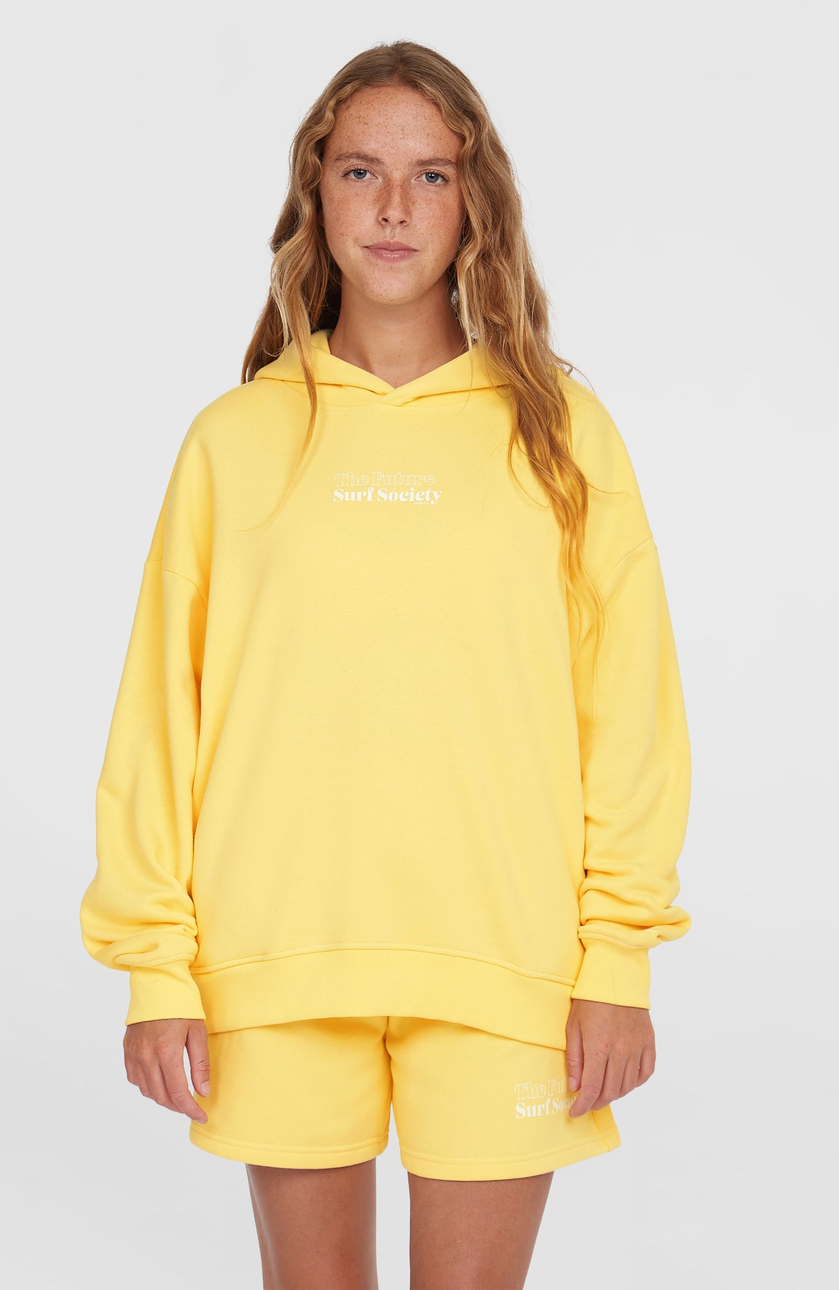 O'Neill Future Surf Society Hoodie für Damen, gelb mit Schriftzug-Print in Weiß, Vorderansicht getragen am Model