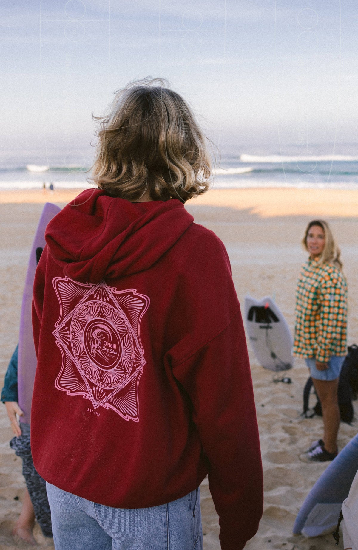 O'Riginals Hoodie für Damen, rot, Detailansicht am Strand mit großflächigem pinkfarbenem Grafik-Print auf der Rückseite