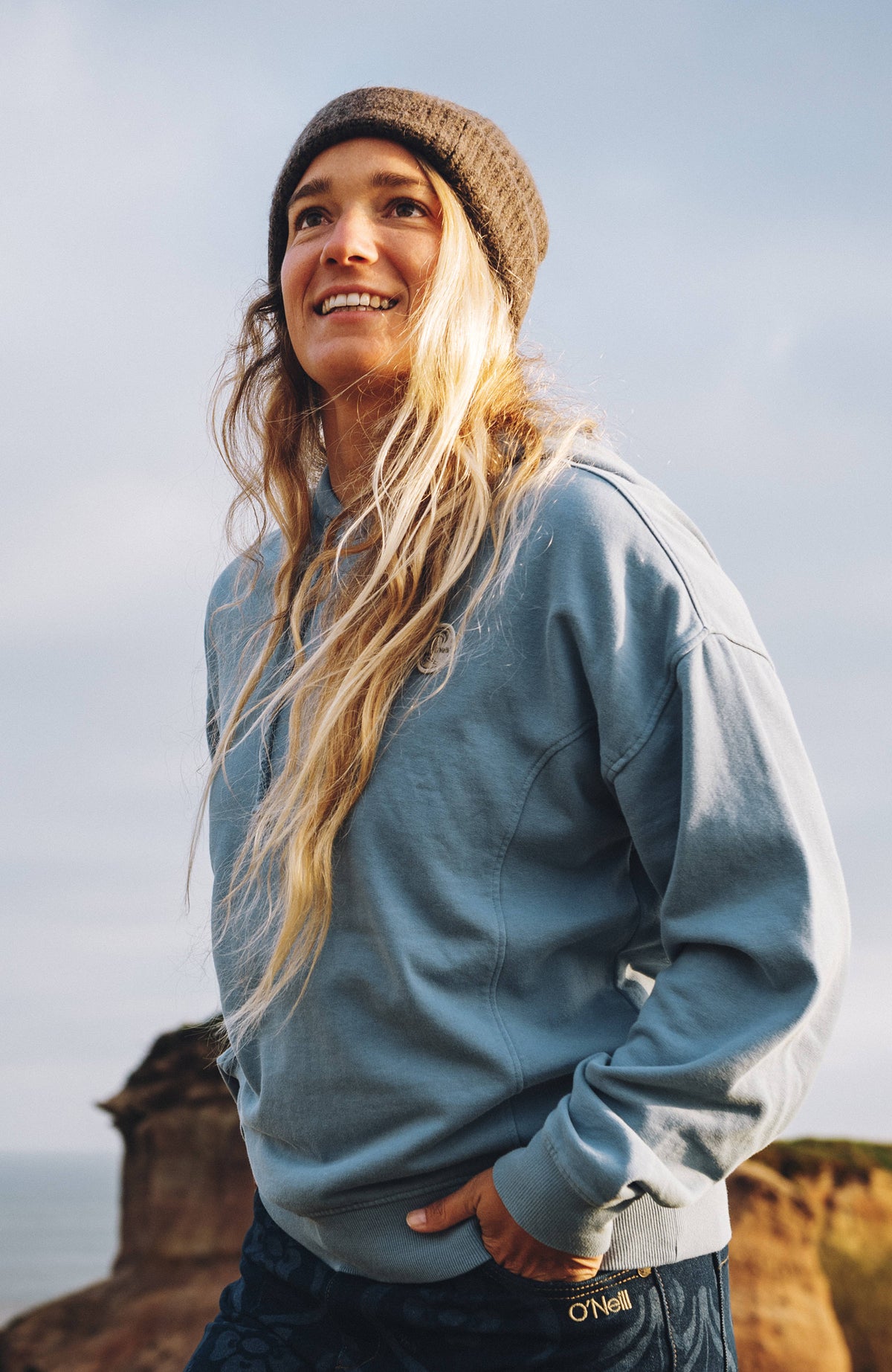 O'Neill O'Riginals Badge Hoodie für Damen, blau, getragen am Model in einer Küstenlandschaft