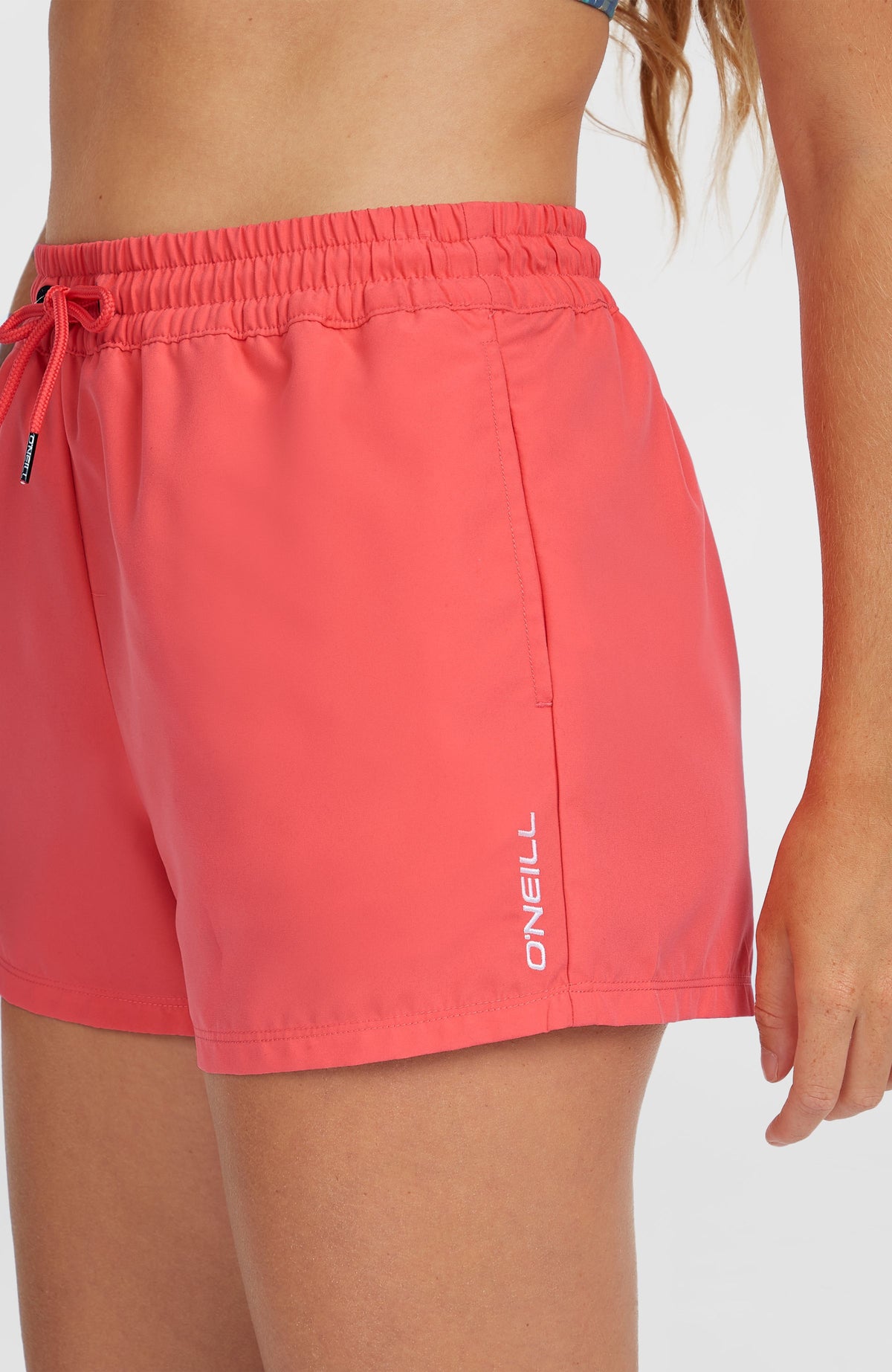 Essentials 12'' Badeshorts für Damen, pink, Nahaufnahme von der Seite am Model mit Logo-Schriftzug am Saum