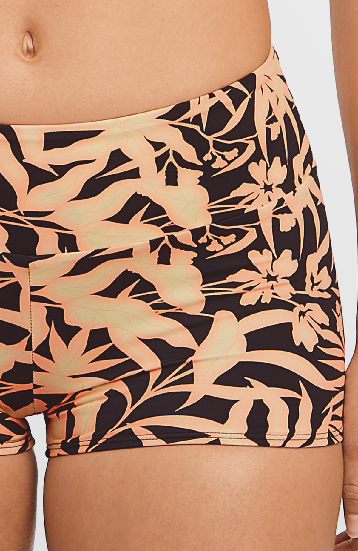 Nahaufnahme der schwarzen Grenada Bikinihose mit Blättermuster in Orange, getragen am Model