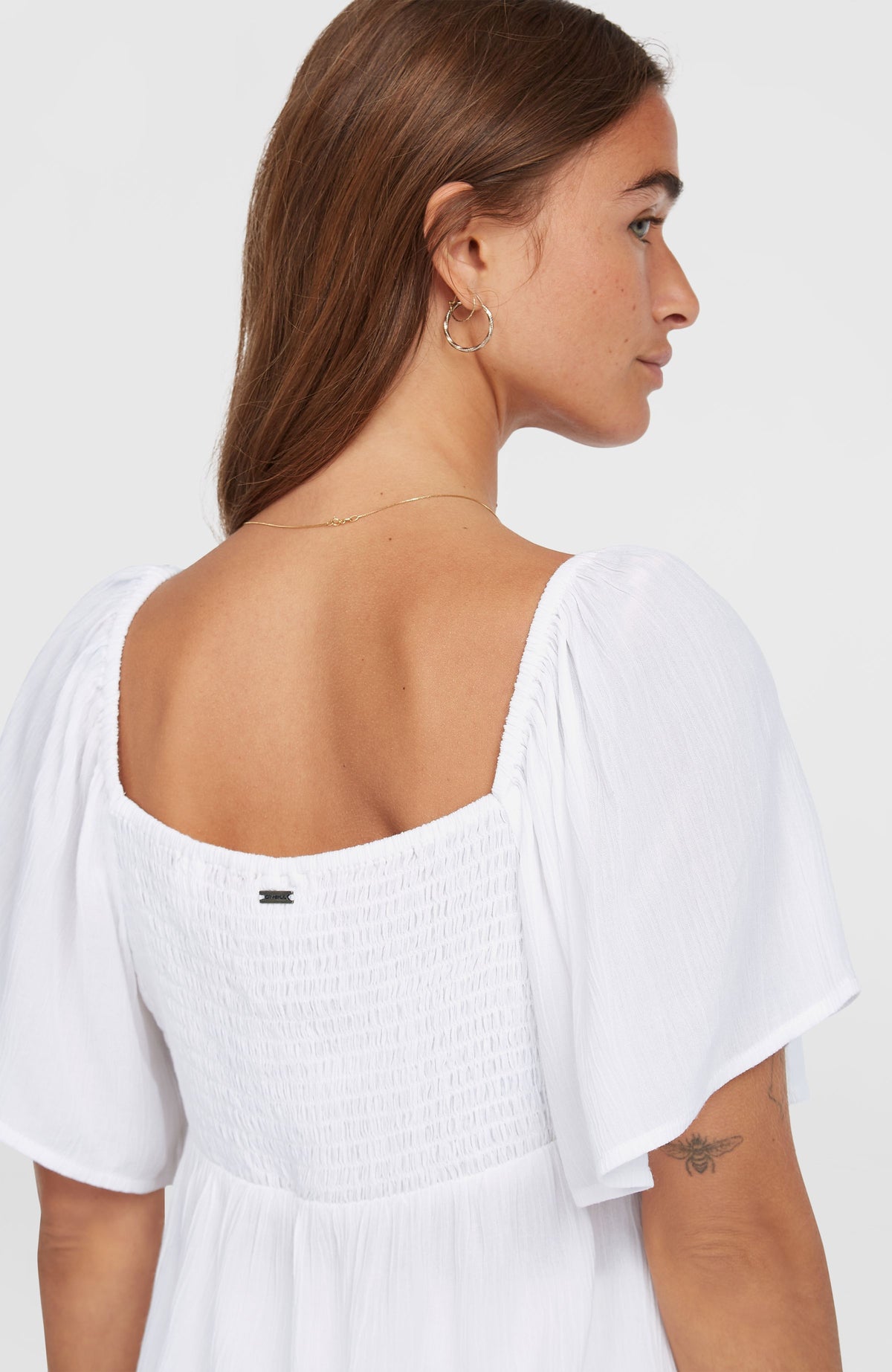 Huges Web-Oberteil für Damen, weiß, Nahaufnahme der Rückseite am Model mit gesmoktem Einsatz und Logo-Badge