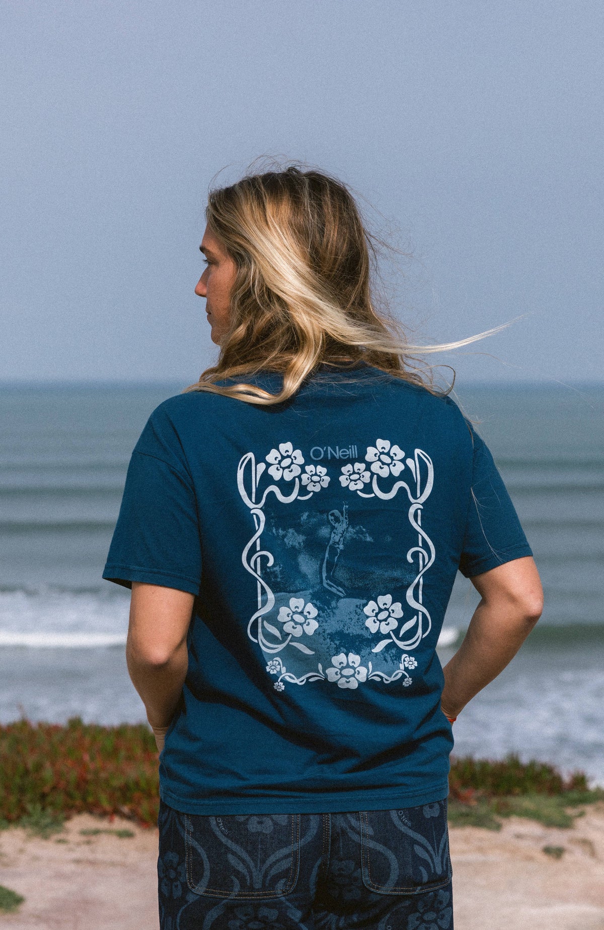 O'Neill O'Riginals Back-Print T-Shirt für Damen, blau mit Grafik-Print in Hellblau und Weiß, Rückansicht am Meer