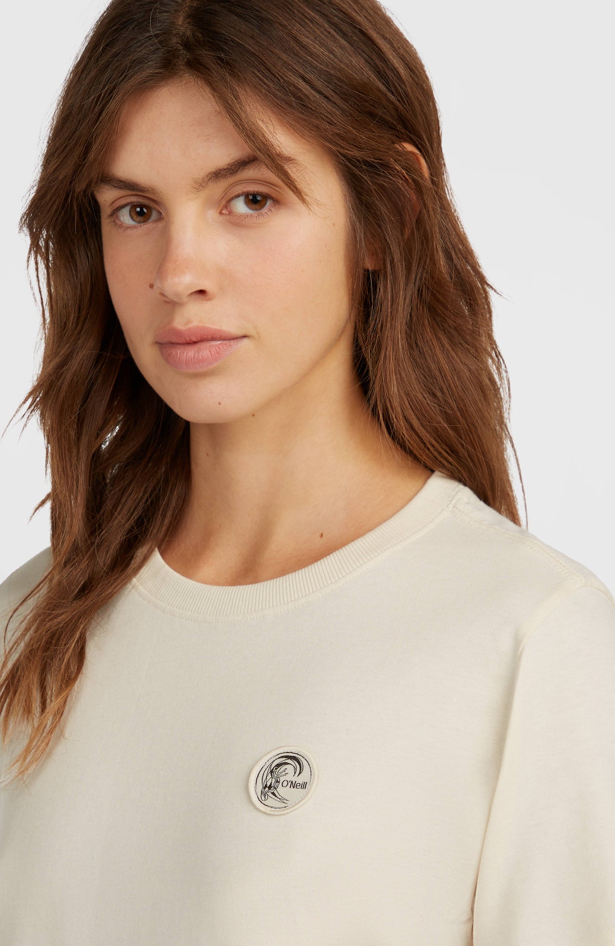 Nahaufnahme des runden Logo-Badges und Rundhalsausschnitts am weißen O'Riginals Badge T-Shirt