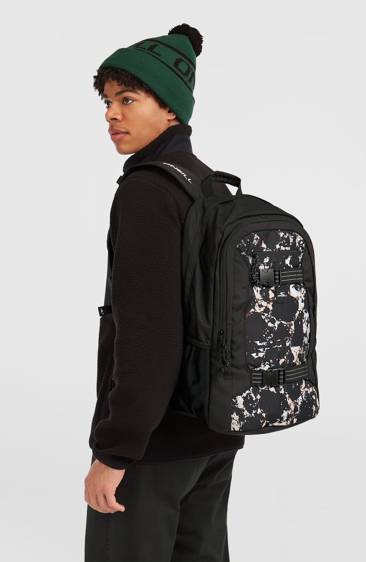 Boarder Rucksack für Herren, schwarz mit Muster in Beige und Weiß, getragen am Model in der Seitenansicht