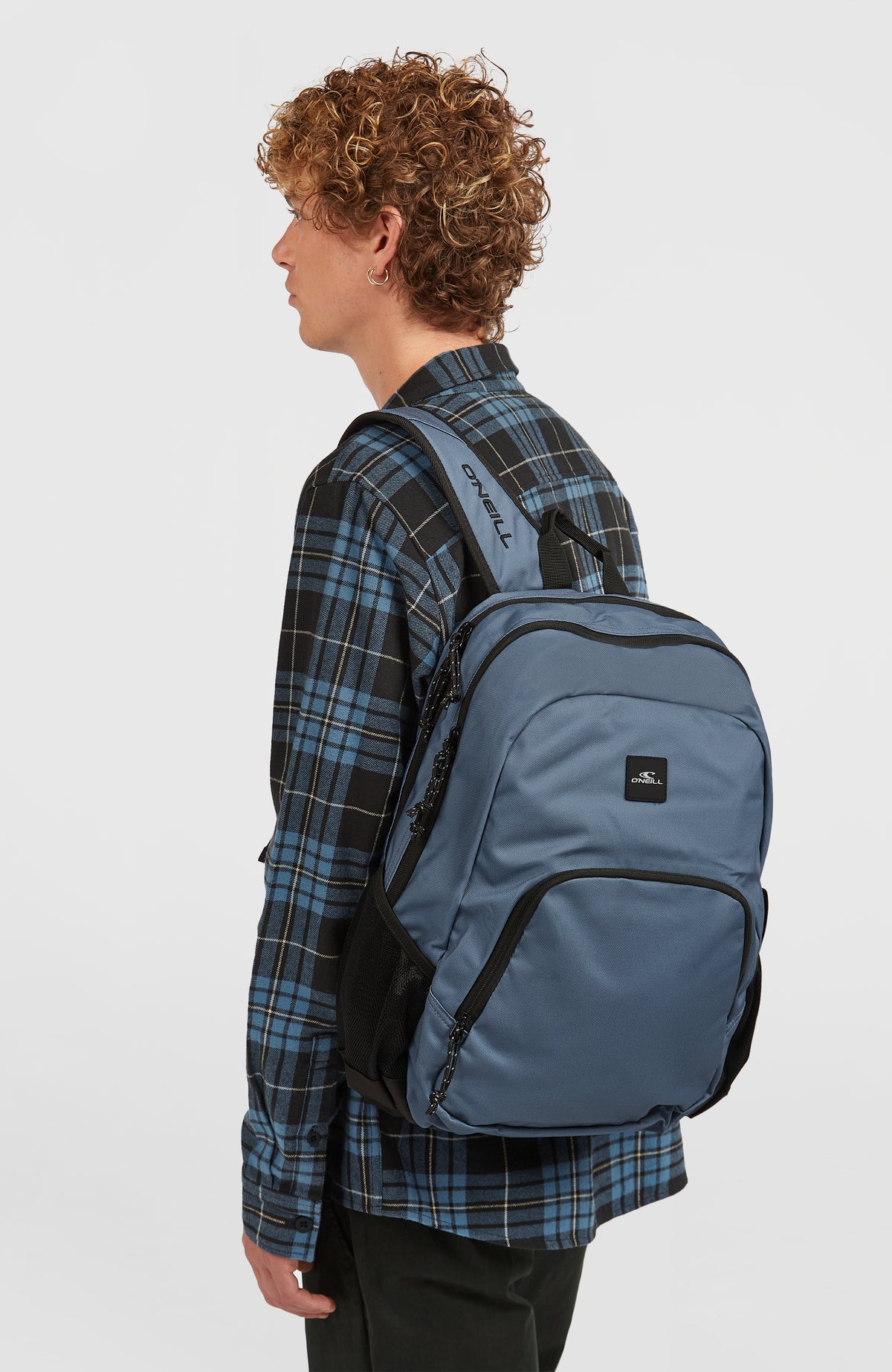 Wedge Rucksack für Herren, blau, getragen am Model von der Seite, Schultergurt mit Logo-Schriftzug