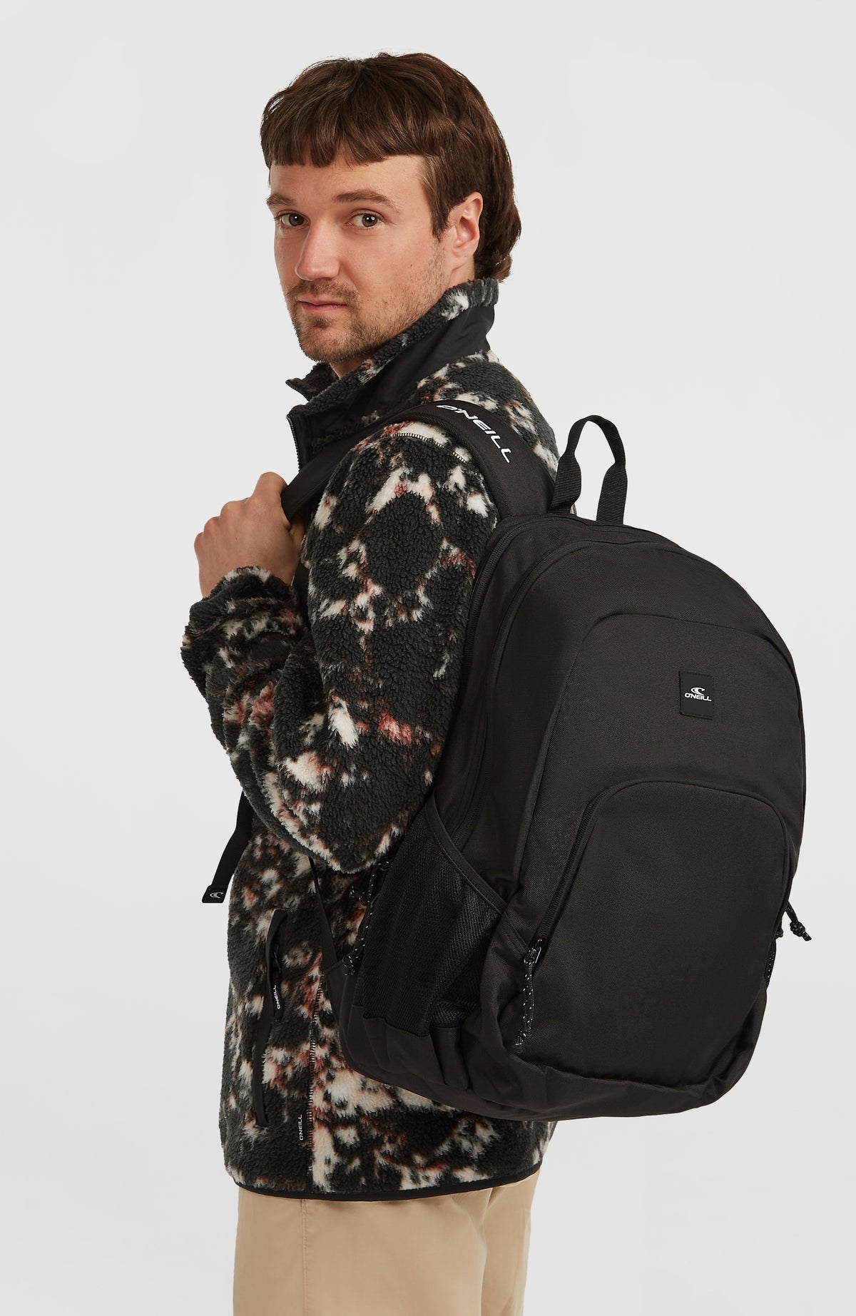 Schwarzer Wedge Rucksack für Herren, getragen am Model, Ansicht von der Seite mit Schultergurt und Seitentasche