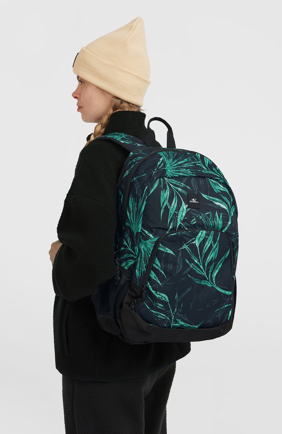 Wedge Rucksack für Herren, blau mit Palmenmuster in Grün, getragen am Model in schräger Rückenansicht