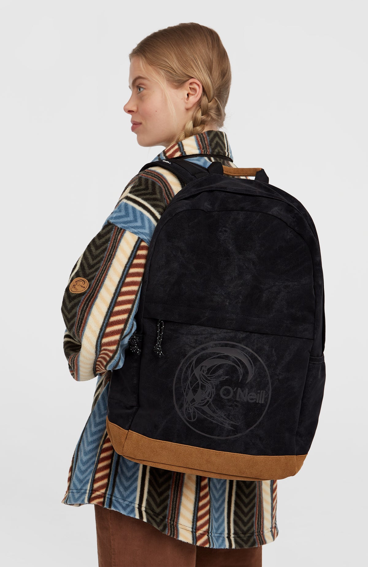 O'Riginals Circle Surfer Rucksack, schwarz, getragen am Model in Seitenansicht mit Reißverschluss-Vortasche