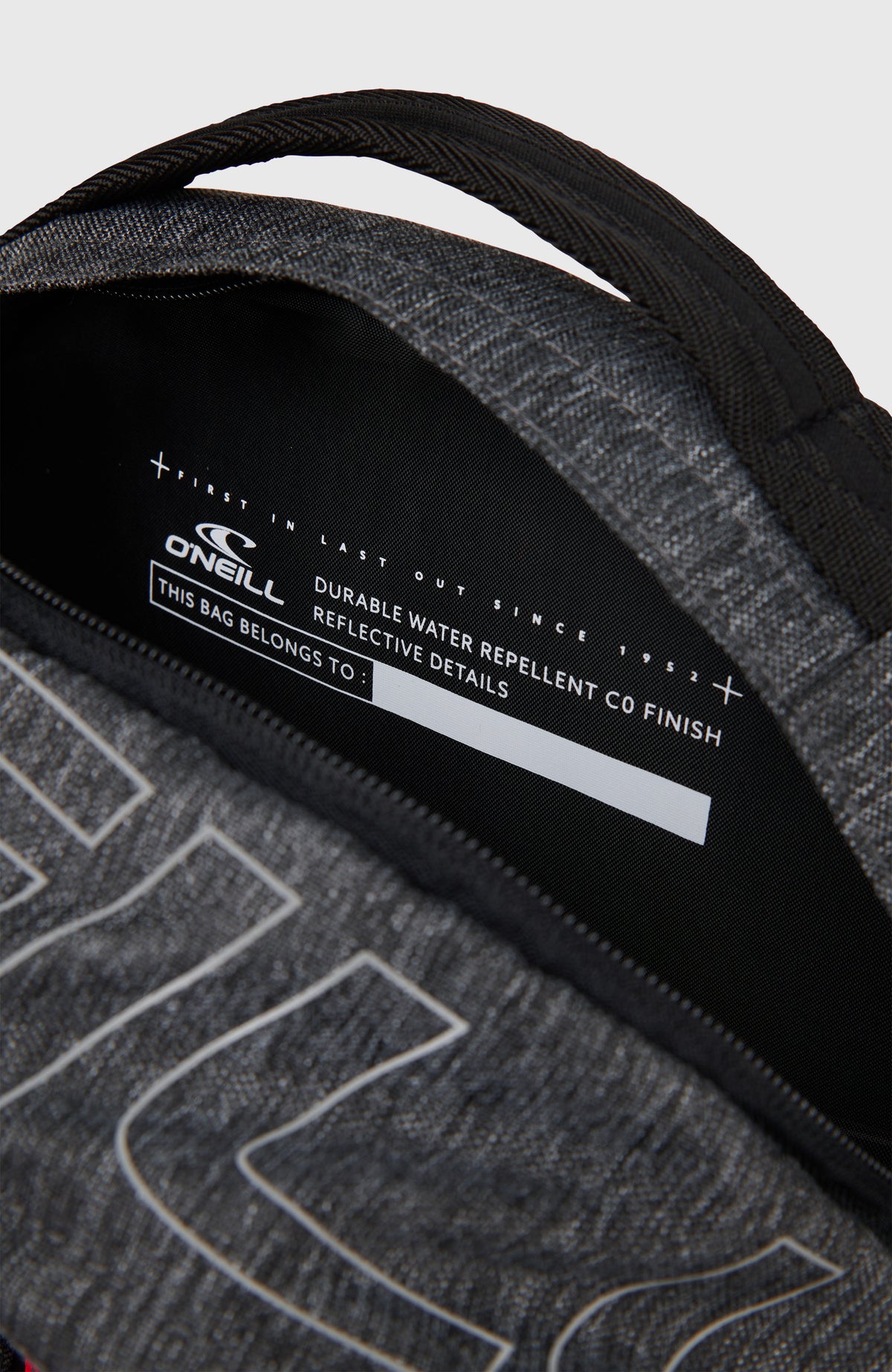 Nahaufnahme des geöffneten oberen Fachs mit Adressfeld und Logo-Aufdruck am grauen President 26L Rucksack