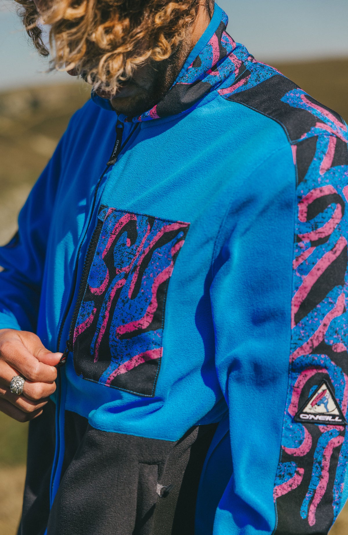 Nahaufnahme der Brusttasche und des Ärmellogos der pinken FWC'Play Polartec® Fleecejacke