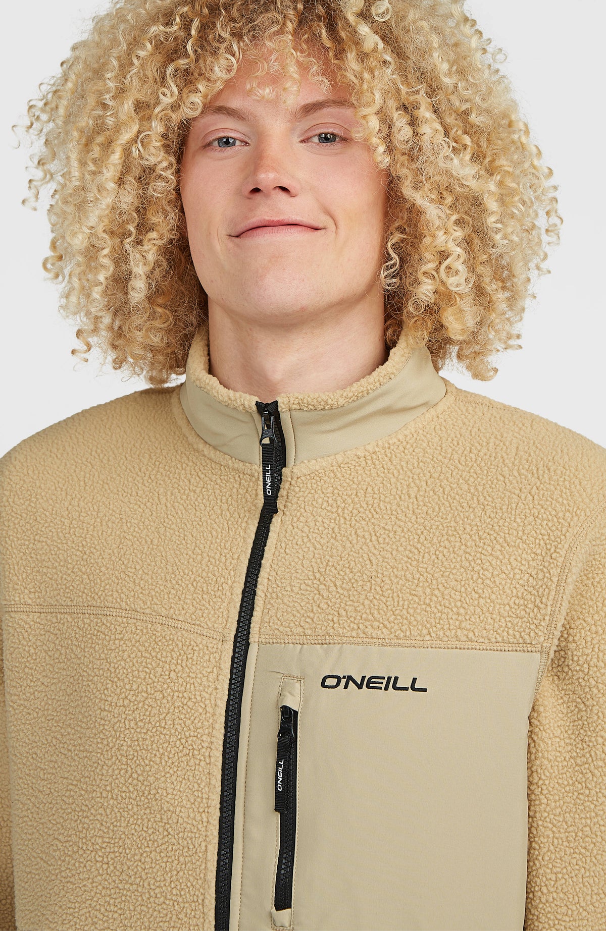 Nahaufnahme der beigen Flauschige Must-Have Fleecejacke am Model, Stehkragen und Brusttasche mit Zipper