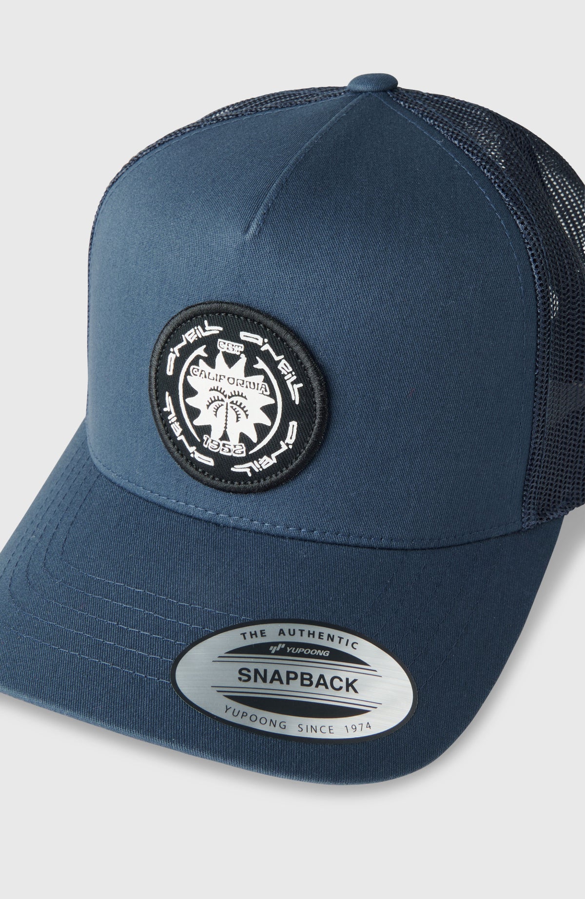 Blaue Retro Trucker Cap für Herren, Nahaufnahme von Schirm und rundem Logo-Aufnäher