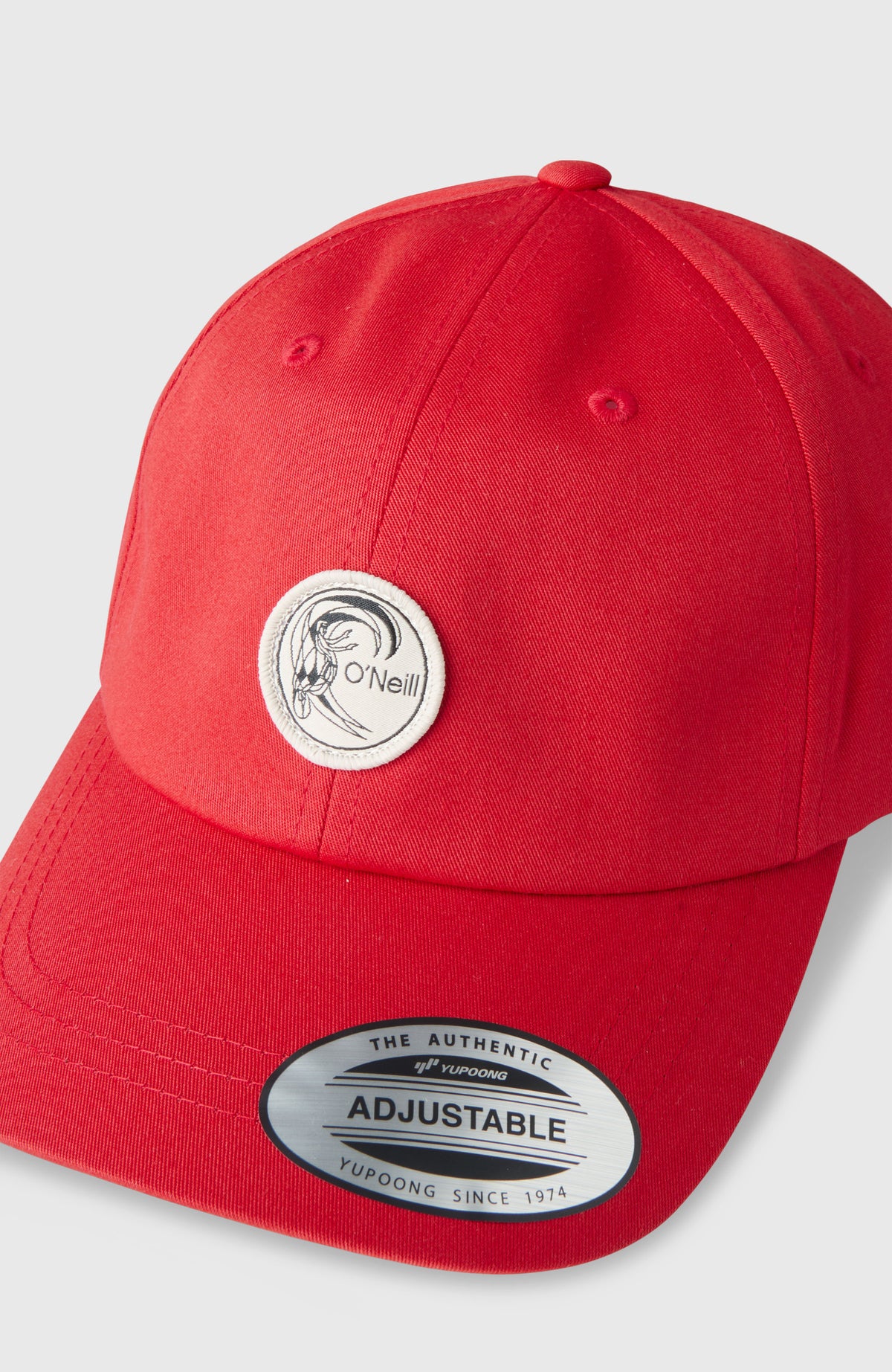 Nahaufnahme der roten O'Riginals Badge Cap, freigestellt von schräg oben mit Logo-Badge