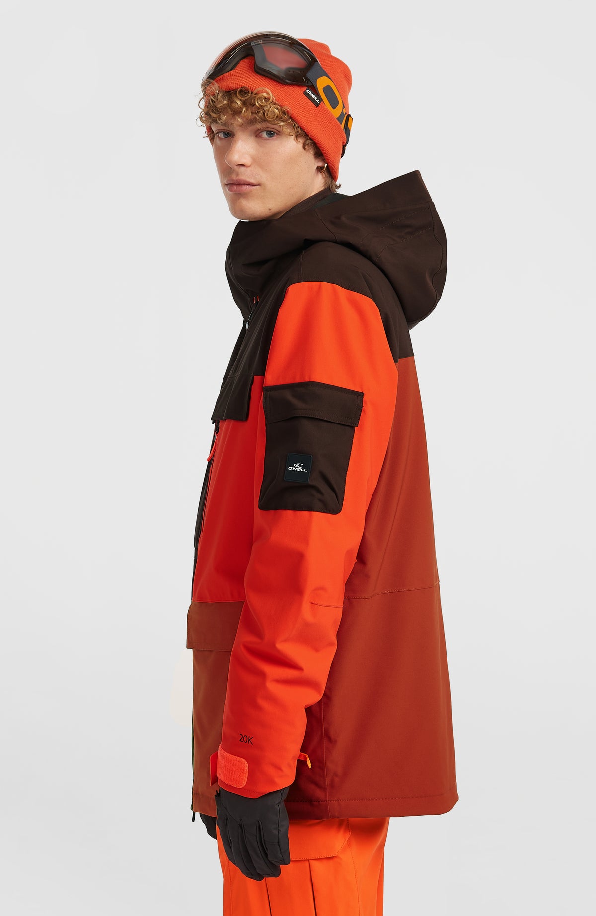 FWC'Peak Pro Skijacke für Herren, orange, Seitenansicht am Model mit aufgesetzter Ärmeltasche und Logo-Badge