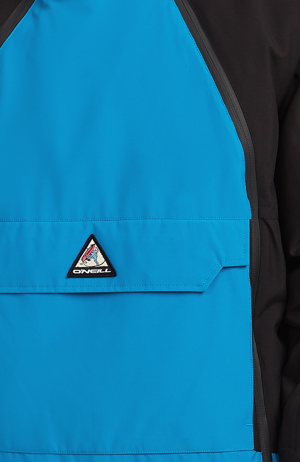 Nahaufnahme der blauen FWC'Play Asymmetric Ski- und Snowboardjacke mit Fronttasche und Logo-Badge