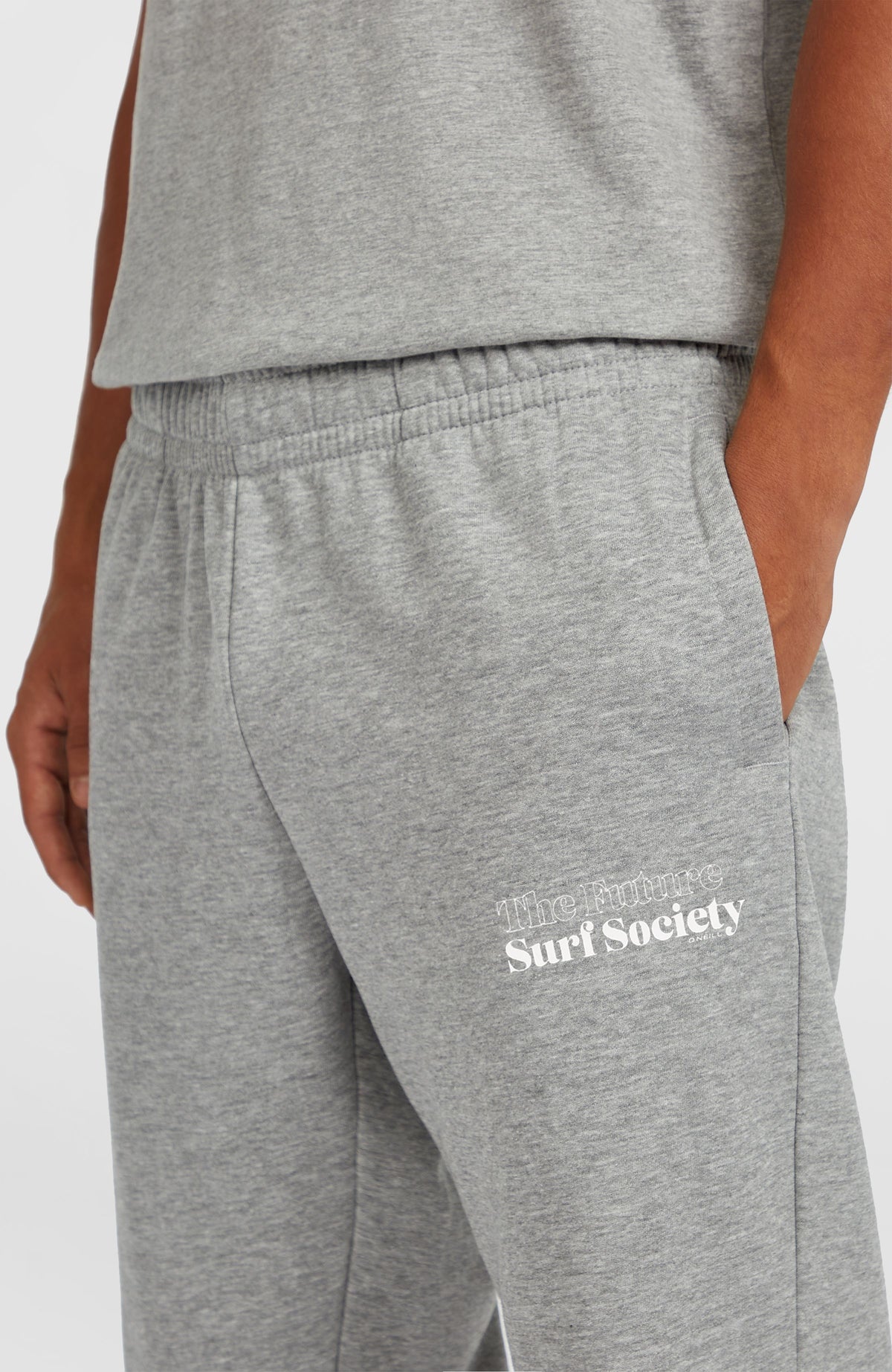 Nahaufnahme der grauen Future Surf Society Jogginghose mit weißem Logo-Print, elastischem Bund und Seitentasche