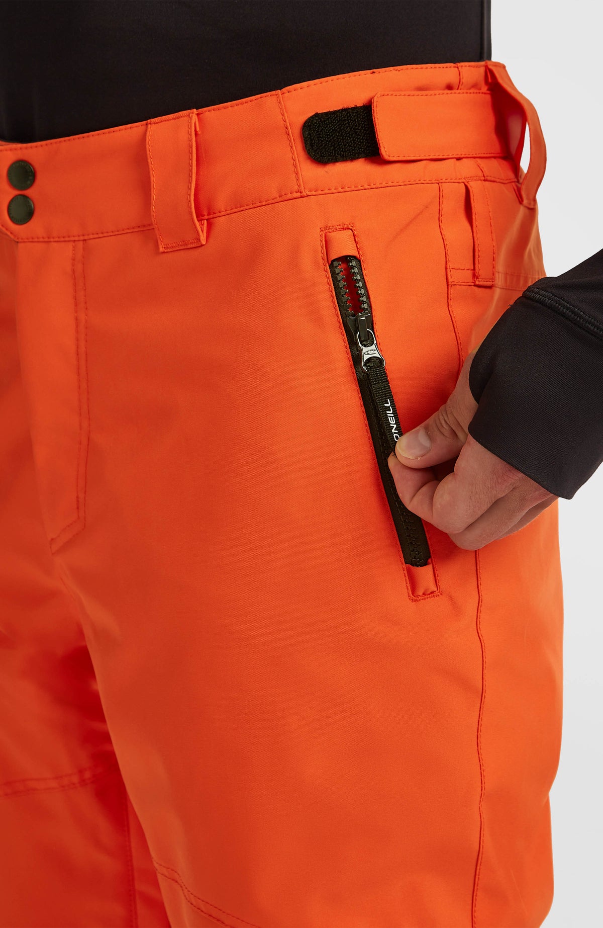 Nahaufnahme von Bund und Reißverschlusstasche der roten FWC'Cruz Skihose am Model
