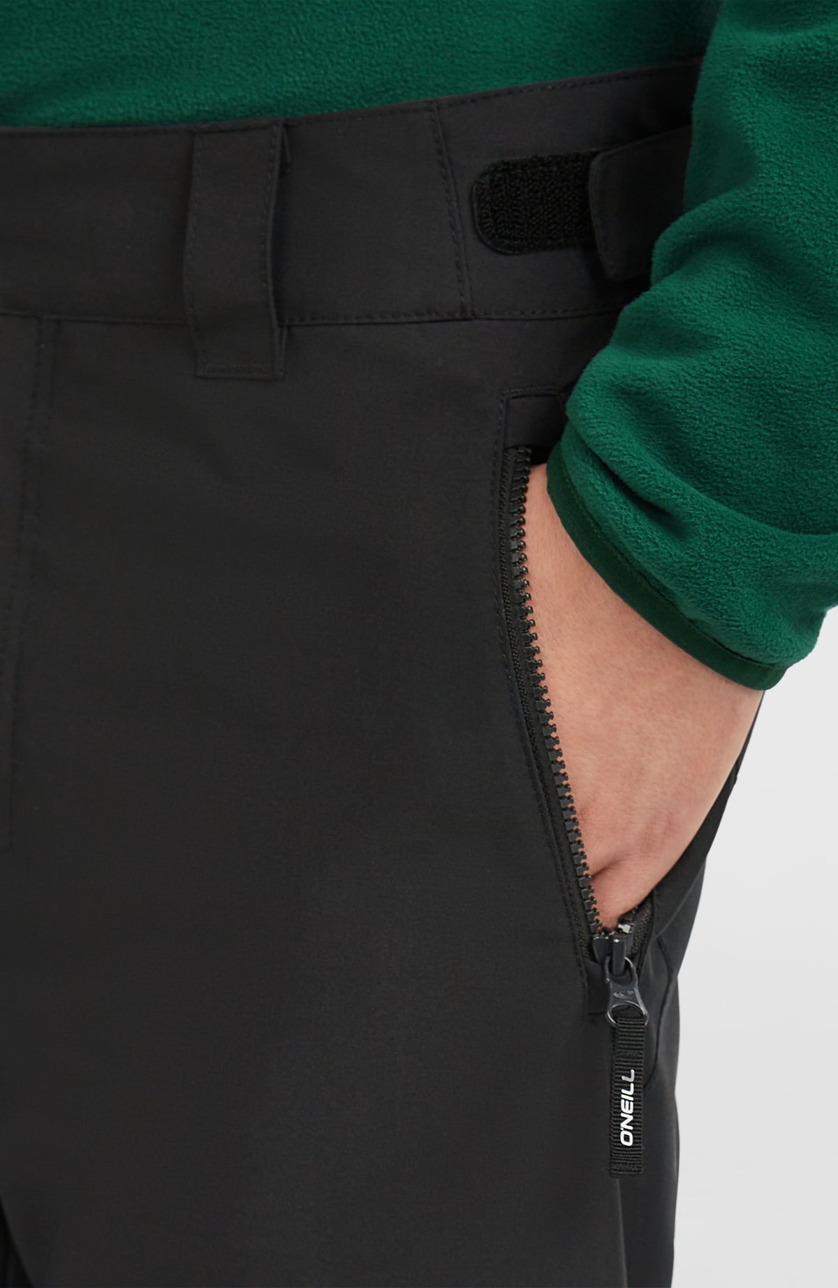 Nahaufnahme der Reißverschlusstasche am Bund der schwarzen FWC'Cruz Skihose am Model