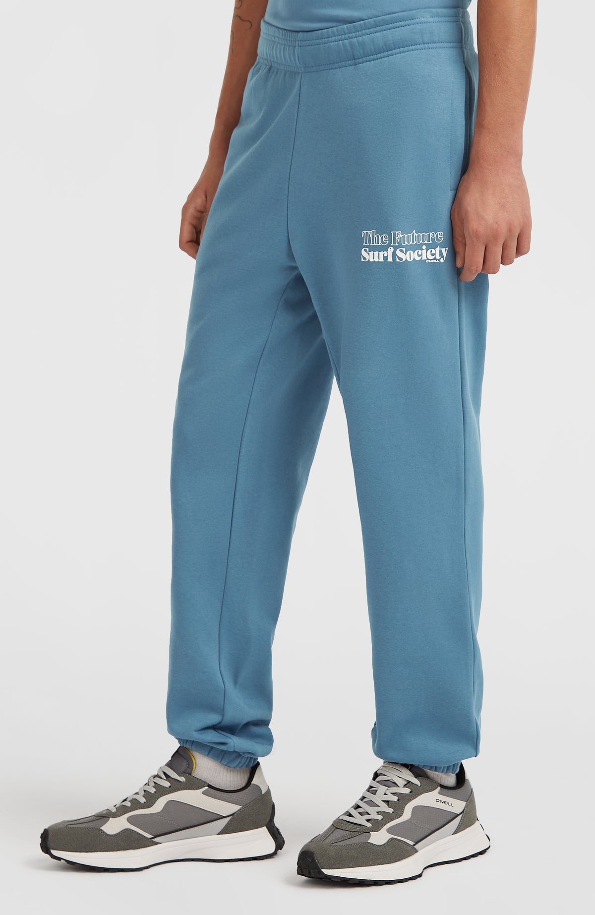 Future Surf Society Jogginghose für Herren, blau mit Logo-Print in Weiß, getragen am Model in der Seitenansicht